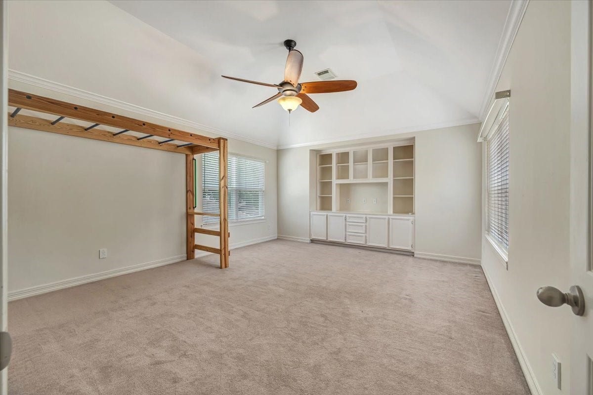 Large game room with built-ins and a custom climbing wall with overhead activity bars, creating a fun and flexible space for play, hobbies or family time.