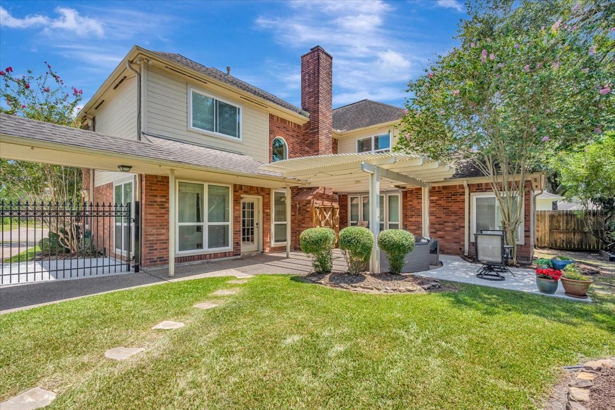 Spacious backyard with an extended patio and pergola, creating a wonderful setting for outdoor dining and entertaining.