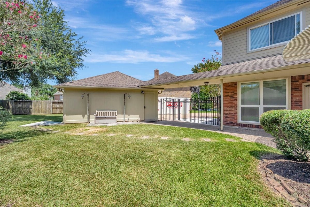 Spacious back yard with an impressive 12' gated opening, offering convenient access to the additional concrete pad and backyard.