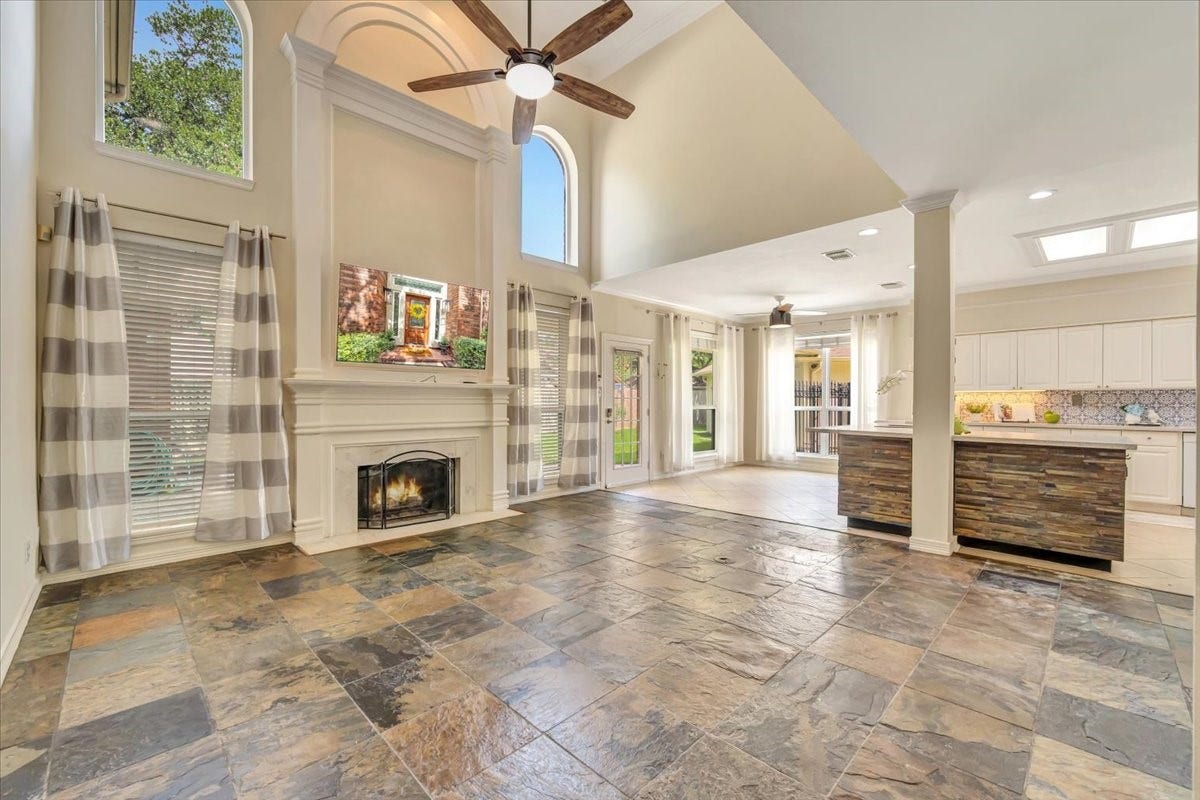 Spacious family room features a fireplace, tall arched windows and beautiful architectural detail