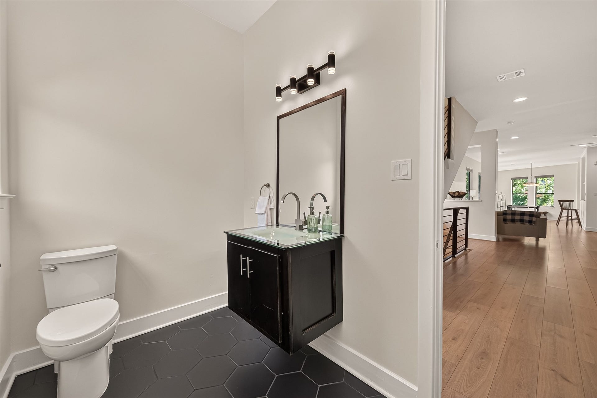 The powder bathroom with a sleek, floating vanity and a large mirror, complemented by the tile floor.