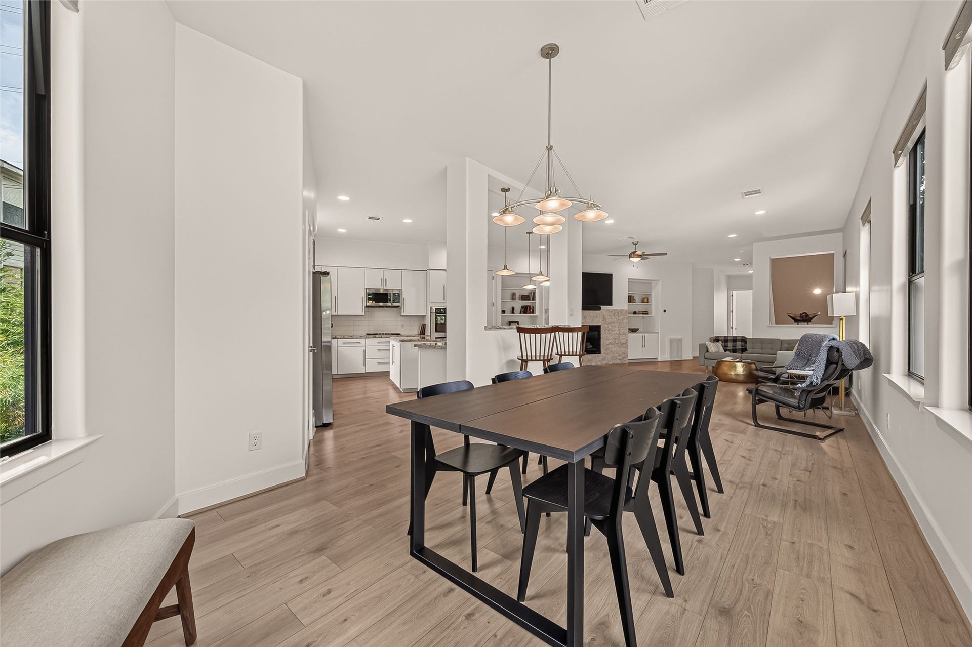 The open-concept living and dining area with sleek light floors and ample natural light. The dining space features contemporary lighting.