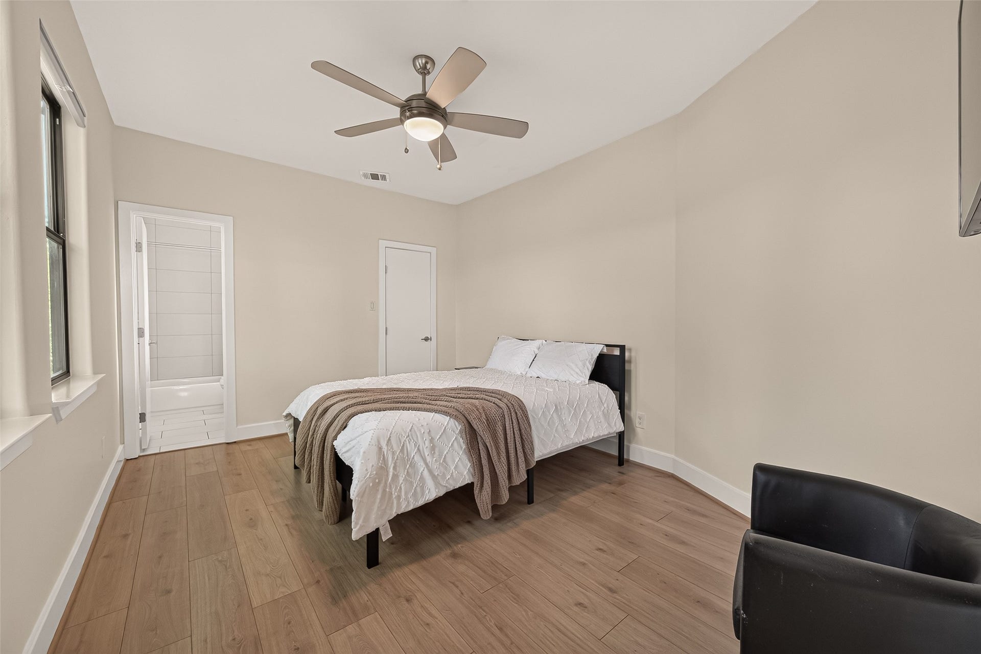 This secondary bedroom is bright and inviting, featuring a neutral color palette and light flooring complete with en-suite bathroom.