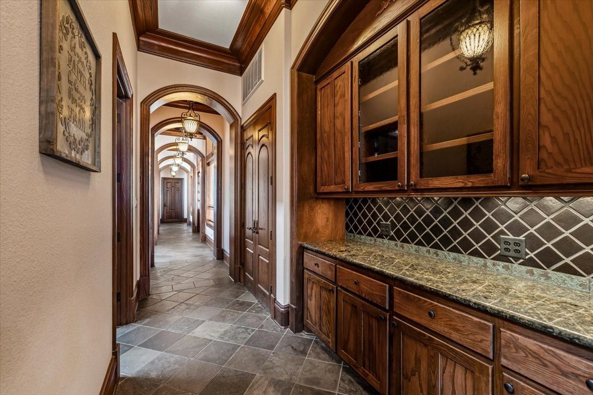 11860 Grand Harbor Boulevard, Montgomery, TX 77356 The downstairs north wing encompasses the full detail of this home. Stunning arches doorways and coffered ceilings. Features another dry bar area, walk-in kitchen pantry, butlers pantry or storage/wrapping room, double doors to courtyard, and entrance to the 4th car single garage and private access to the 4th bedroom suite.
