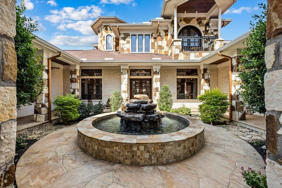 11860 Grand Harbor Boulevard, Montgomery, TX 77356 Breathtaking entrance into the courtyard. Iron gates, plus solid wood doors invite into this area, surrounded by the north and south wings of the home. Centered with a beautiful fountain, plus covered patio seating all around.