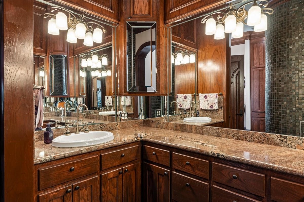 11860 Grand Harbor Boulevard, Montgomery, TX 77356 Primary bathroom offers a dramatic effect with darkwoods, moody lights and full of cabinets.