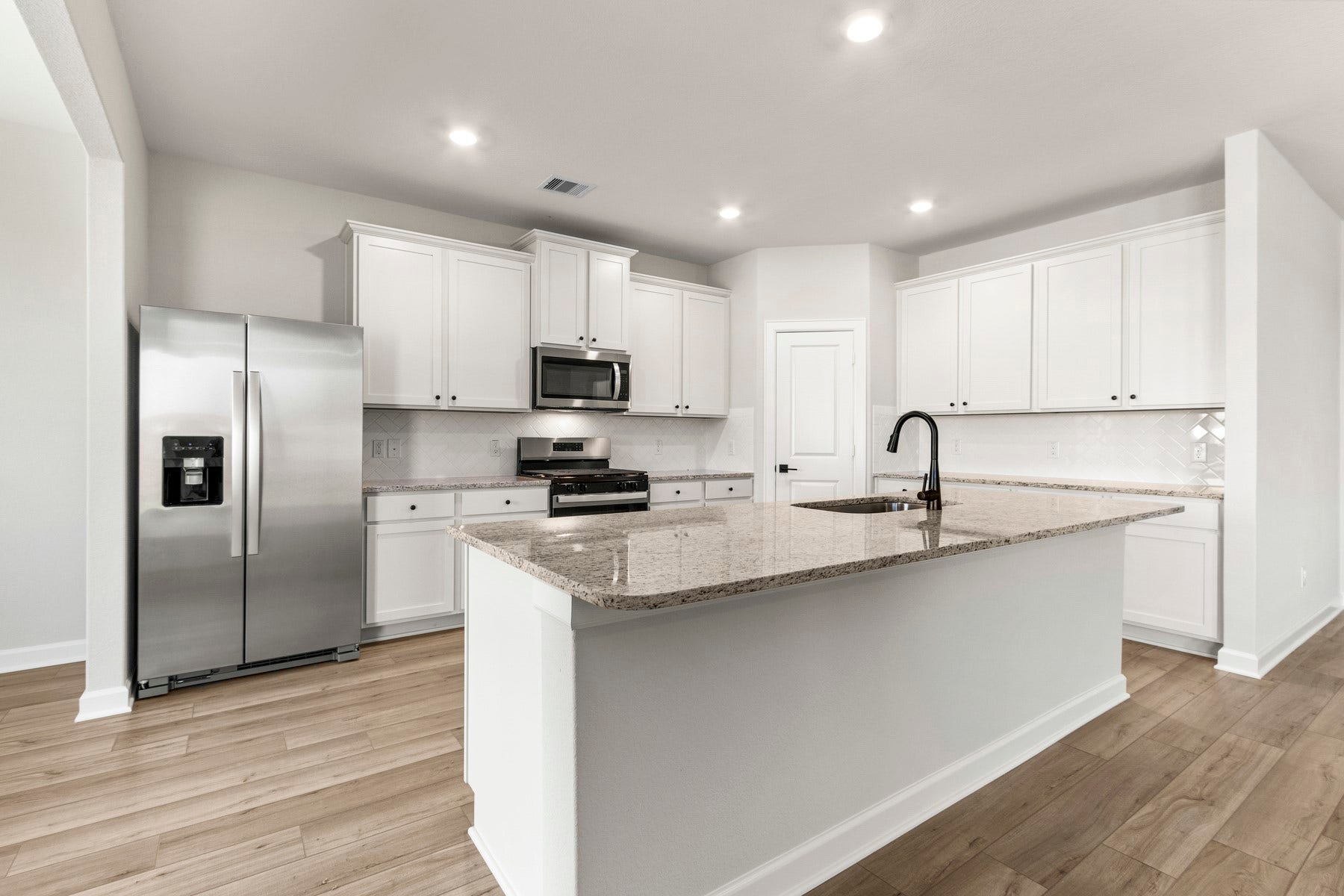 14001 Starboard Reach Drive, Texas City, TX 77510 The kitchen features large island with sink and breakfast bar, beautiful white cabinetry, and stainless steel appliances.