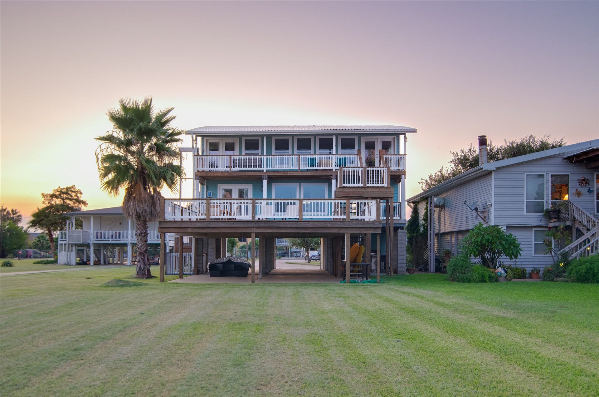 1309 8th Street, San Leon, TX 77539 From the bay, the home presents a stunning waterfront view, showcasing a spacious balcony and an expansive deck that stretch across the rear of the house. Large windows reflect the water and invite natural light inside, hinting at the bright, airy interiors beyond. The combination of outdoor living spaces and panoramic windows creates a striking, inviting faade that perfectly complements the tranquil bay setting.