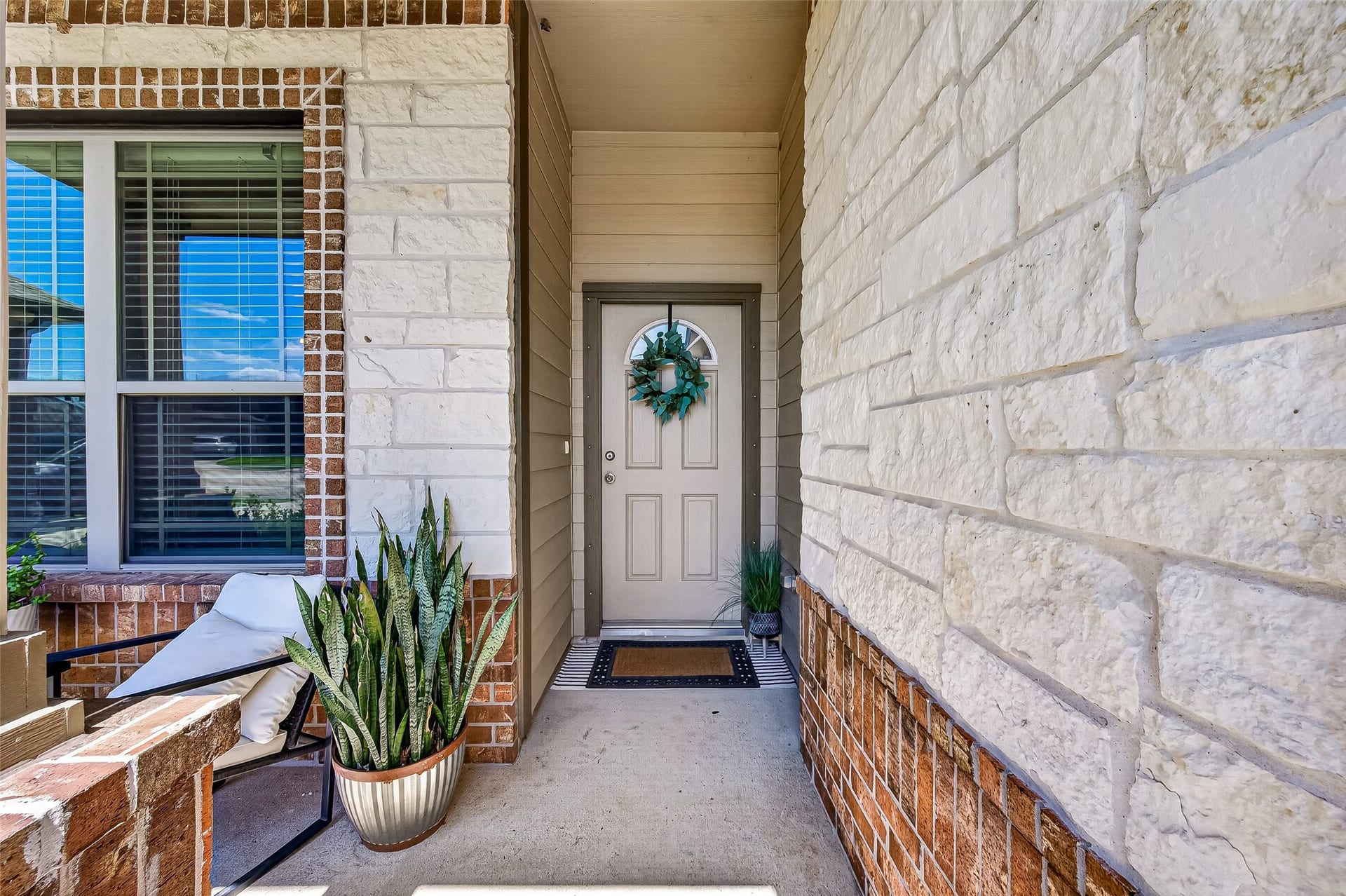 8422 Black Pearl Court, Texas City, TX 77591 Charming entryway with stone and brick accents, featuring a welcoming front door adorned with a decorative wreath and surrounded by lush potted plants.
