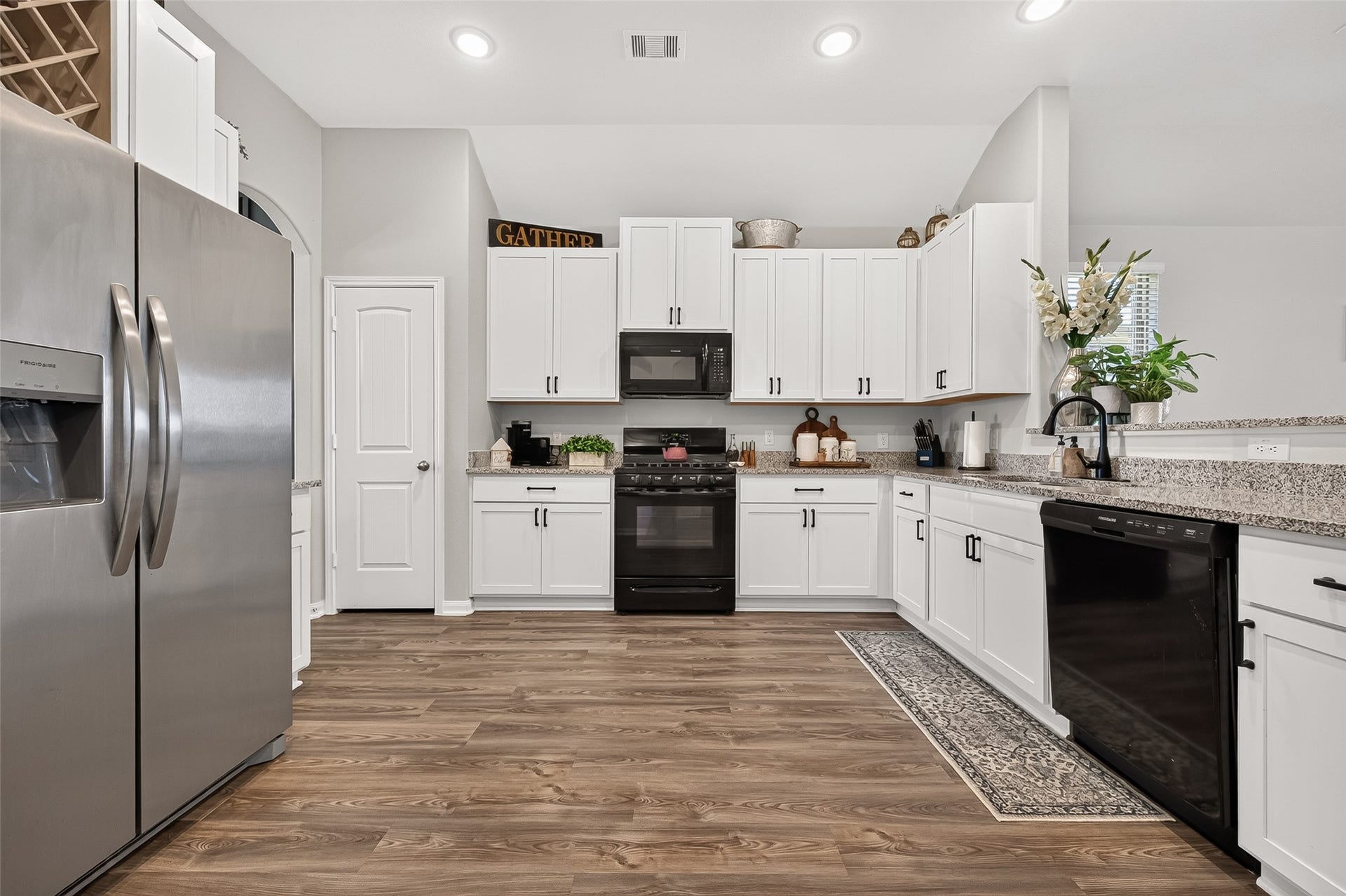 8422 Black Pearl Court, Texas City, TX 77591 Modern kitchen featuring sleek stainless steel appliances, elegant white cabinetry, and beautiful wood flooring, creating a warm and inviting space for cooking and entertaining.