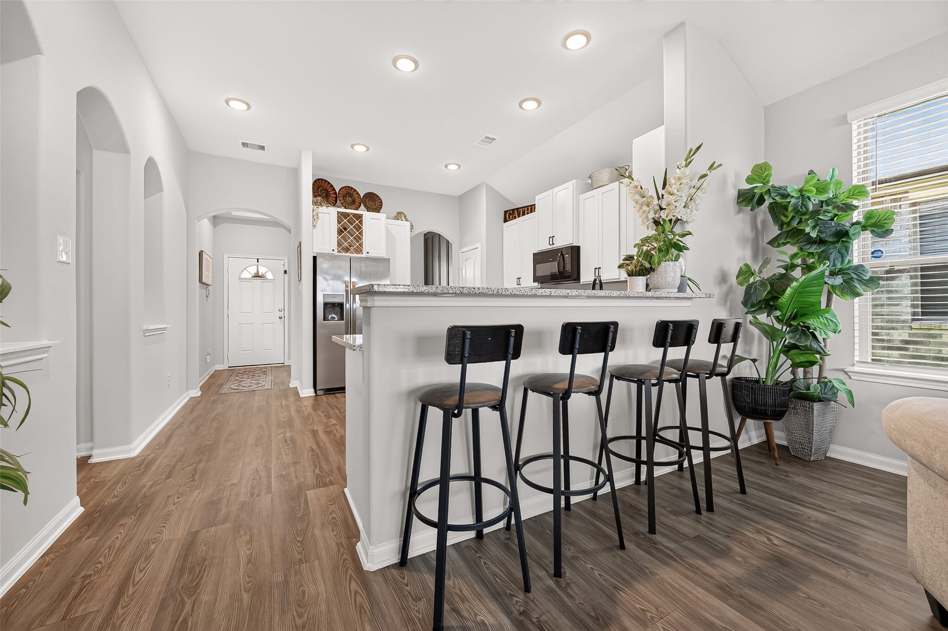 8422 Black Pearl Court, Texas City, TX 77591 Modern kitchen features a spacious breakfast bar with sleek black stools, complemented by beautiful hardwood floors and abundant natural light.