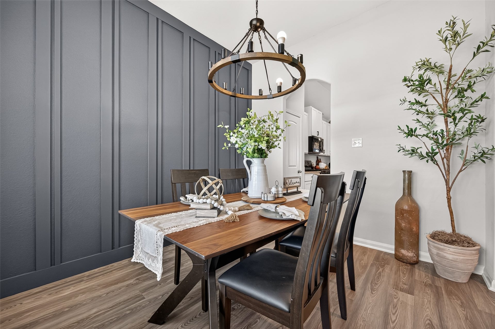 8422 Black Pearl Court, Texas City, TX 77591 Elegant dining area featuring a stylish wood table, modern chandelier, and a striking dark paneled accent wall.