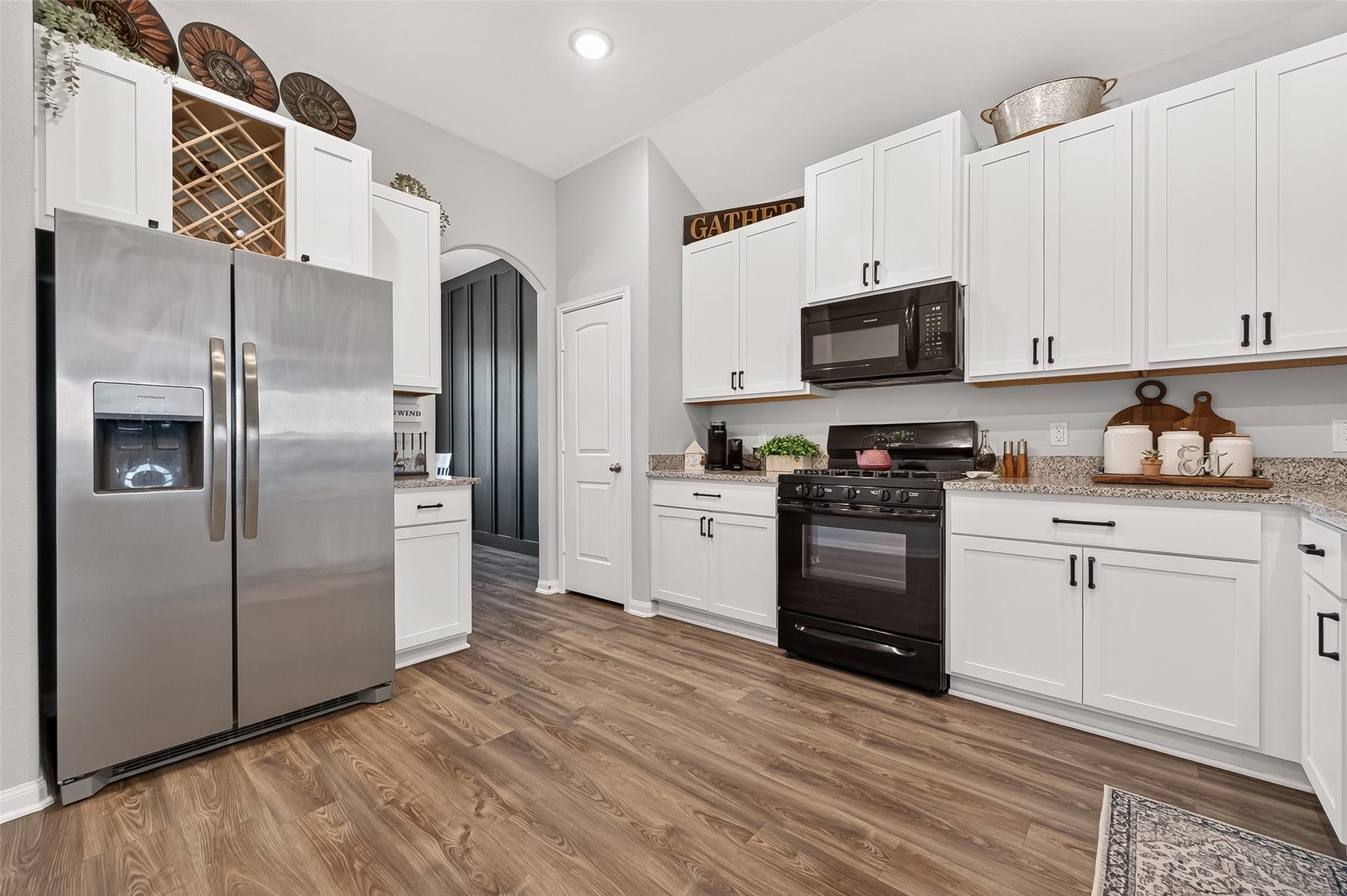 8422 Black Pearl Court, Texas City, TX 77591 The kitchen features sleek stainless steel appliances, elegant white cabinetry with black hardware, and warm wood flooring, creating a modern and inviting space.