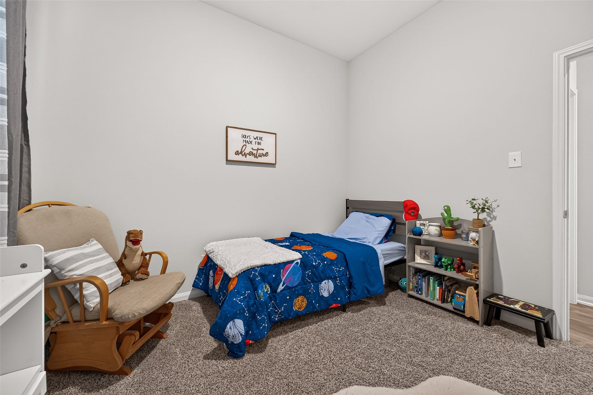 8422 Black Pearl Court, Texas City, TX 77591 Cozy children's bedroom featuring a space-themed bedspread, plush carpeting, and a charming reading nook with a rocking chair.