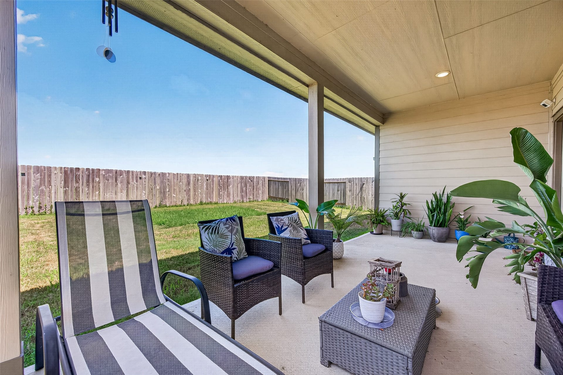 8422 Black Pearl Court, Texas City, TX 77591 Relax in this inviting covered patio featuring comfortable seating, lush greenery, and a spacious fenced yard perfect for outdoor enjoyment.