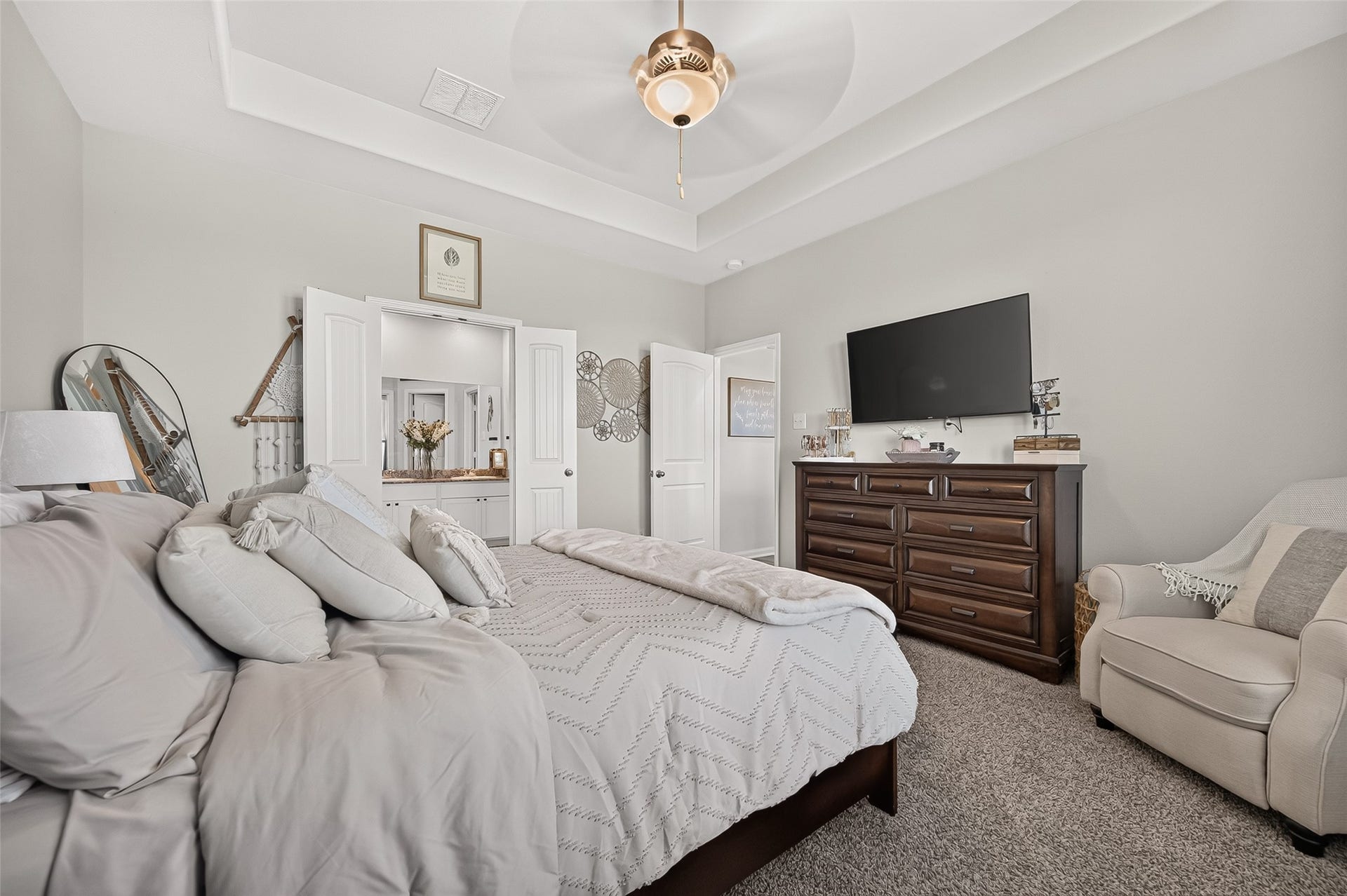 8422 Black Pearl Court, Texas City, TX 77591 Spacious bedroom featuring a cozy bed with plush pillows, a large dresser with a mounted TV, and an inviting armchair, all set under a stylish ceiling fan and soft neutral tones.