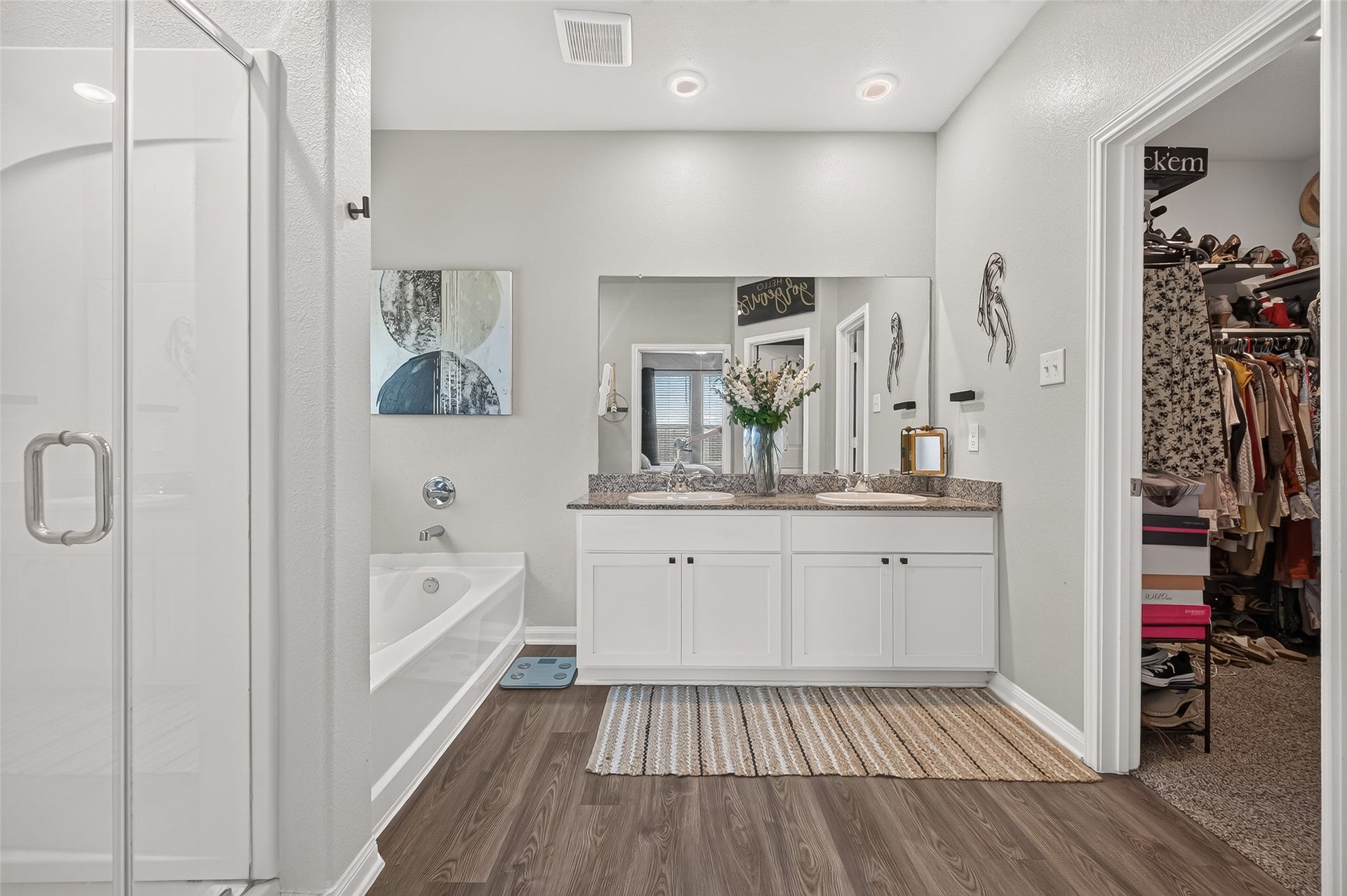 8422 Black Pearl Court, Texas City, TX 77591 Spacious bathroom featuring a double vanity with granite countertops, a soaking tub, and a glass-enclosed shower, complemented by a walk-in closet.