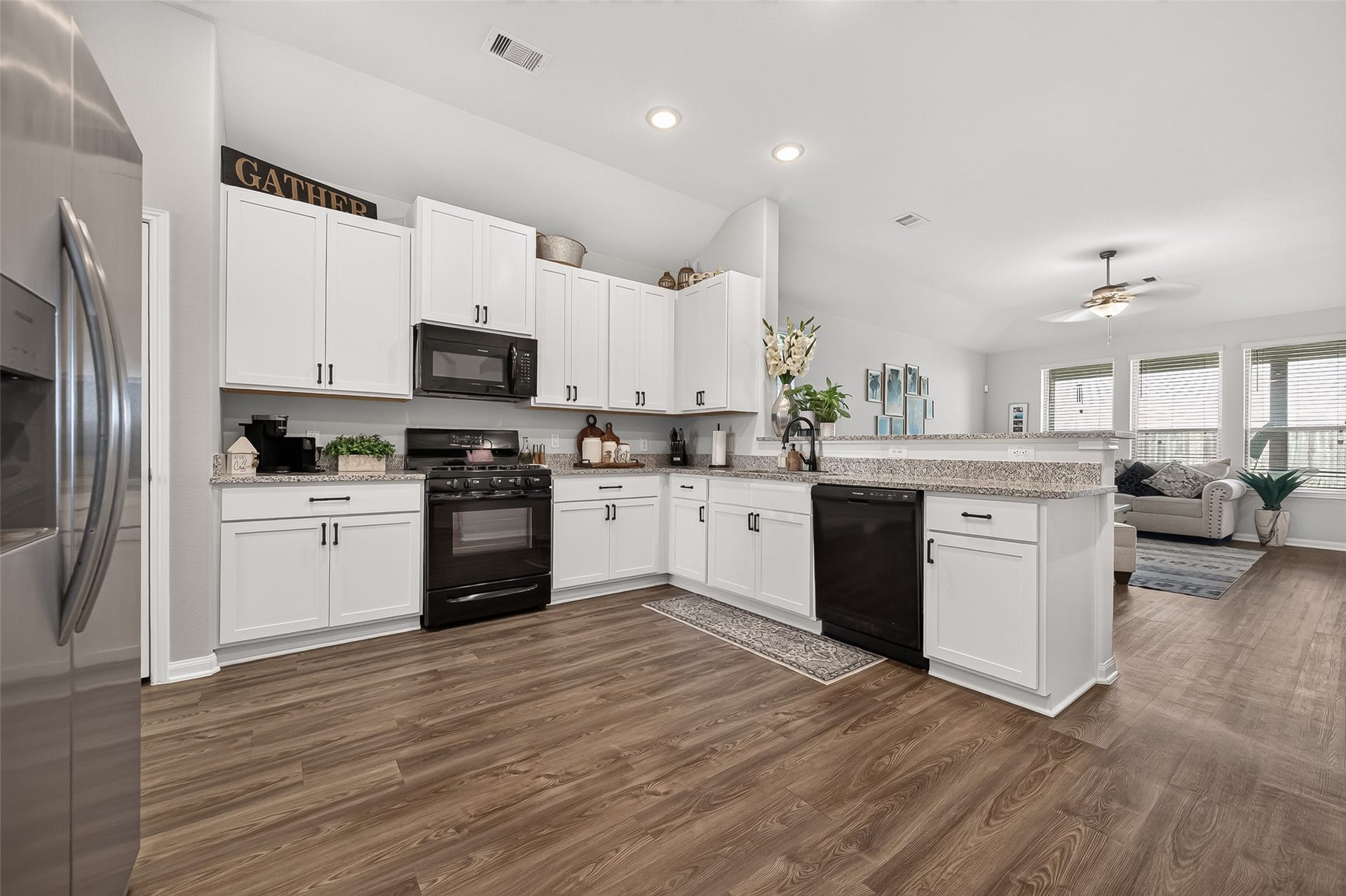 8422 Black Pearl Court, Texas City, TX 77591 Spacious kitchen with modern appliances, elegant white cabinetry, and sleek granite countertops, seamlessly flowing into a bright, inviting living area.