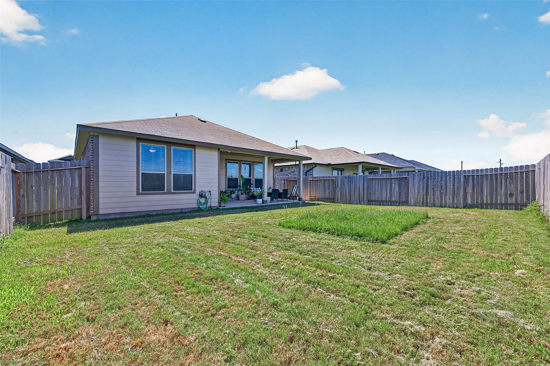 8422 Black Pearl Court, Texas City, TX 77591 Spacious backyard with well-maintained lawn, privacy fence, and a cozy covered patio perfect for outdoor relaxation and entertaining.