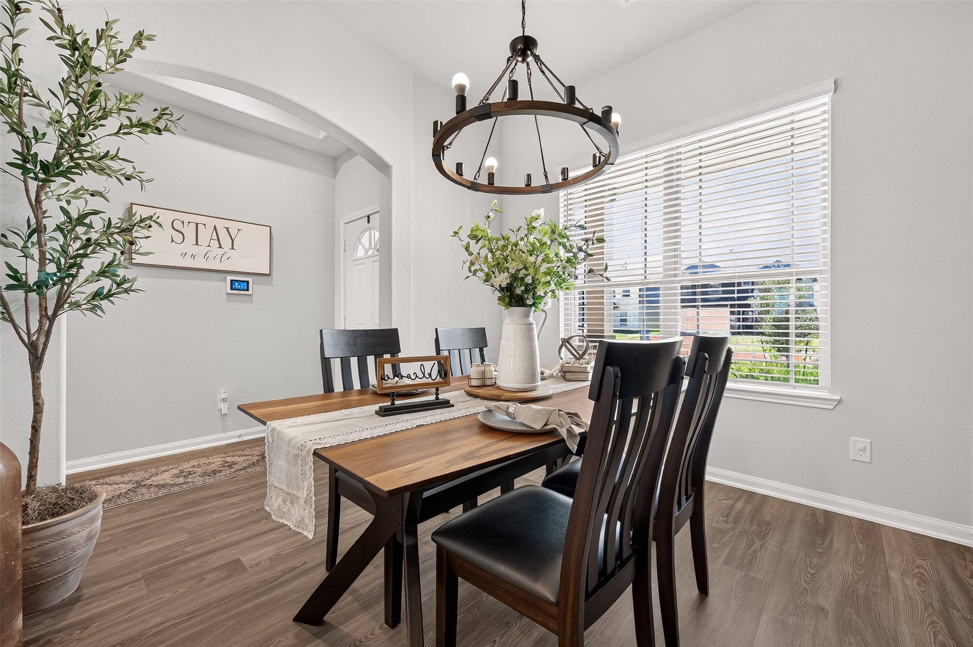 8422 Black Pearl Court, Texas City, TX 77591 Bright and inviting dining area featuring a rustic wooden table, elegant chandelier, and ample natural light from large windows, creating a perfect space for gatherings.