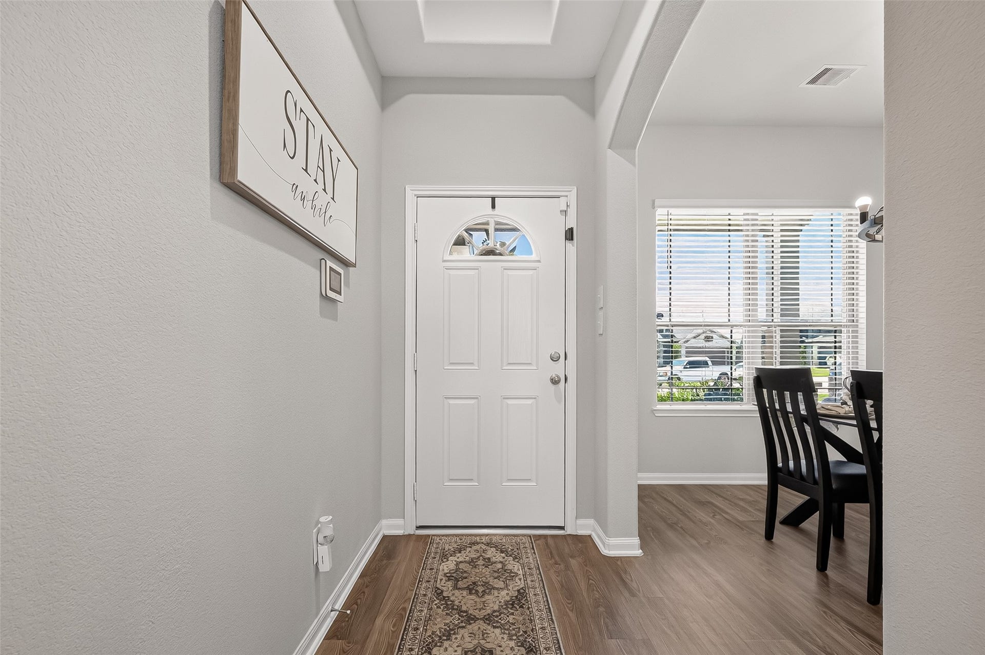 8422 Black Pearl Court, Texas City, TX 77591 Inviting entryway featuring a white front door, elegant wood flooring, and an arched opening leading to a bright dining area with large windows.
