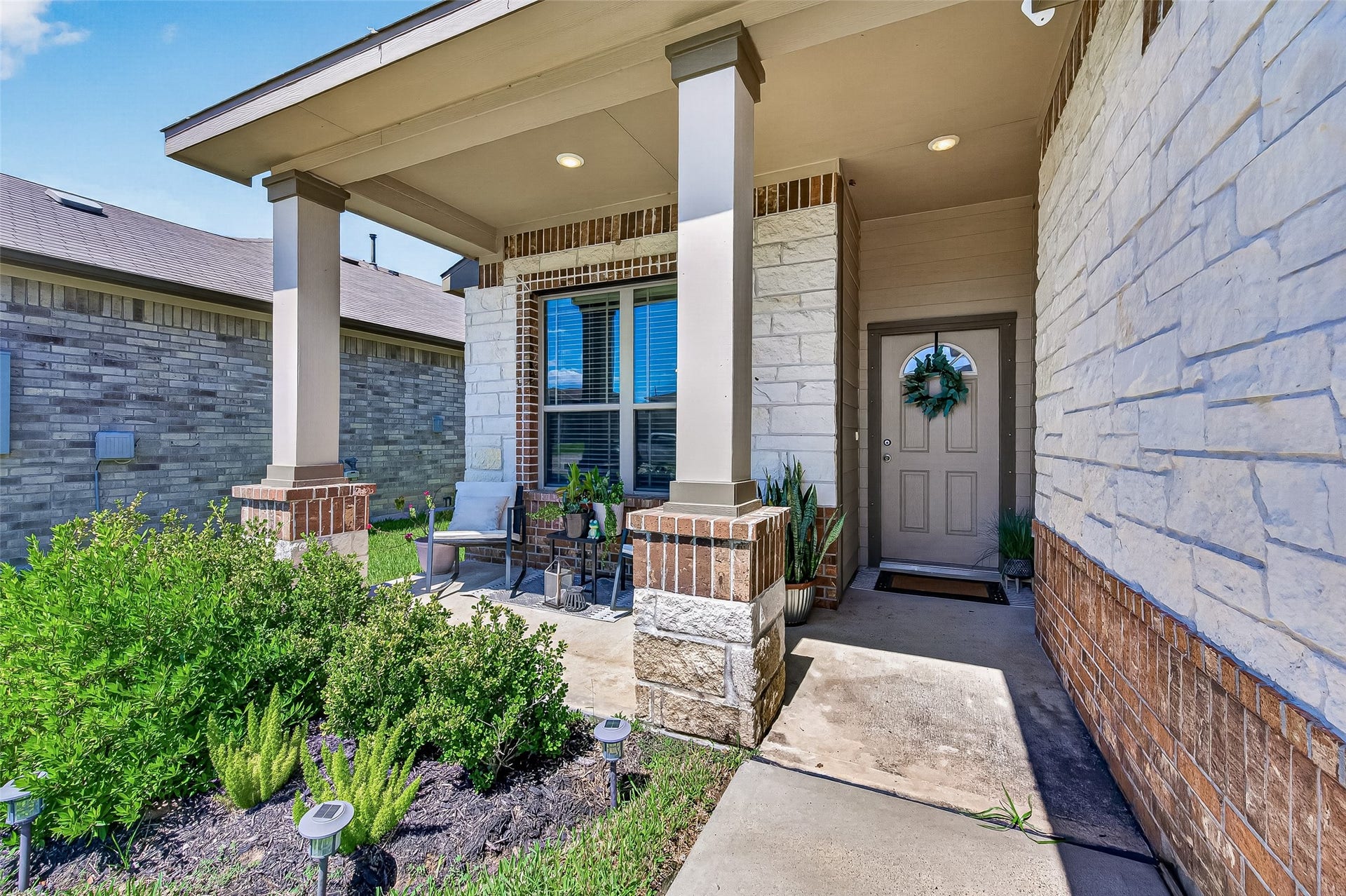 8422 Black Pearl Court, Texas City, TX 77591 Charming front porch with elegant stone accents, inviting seating area, and lush greenery, offering a warm and welcoming entrance.
