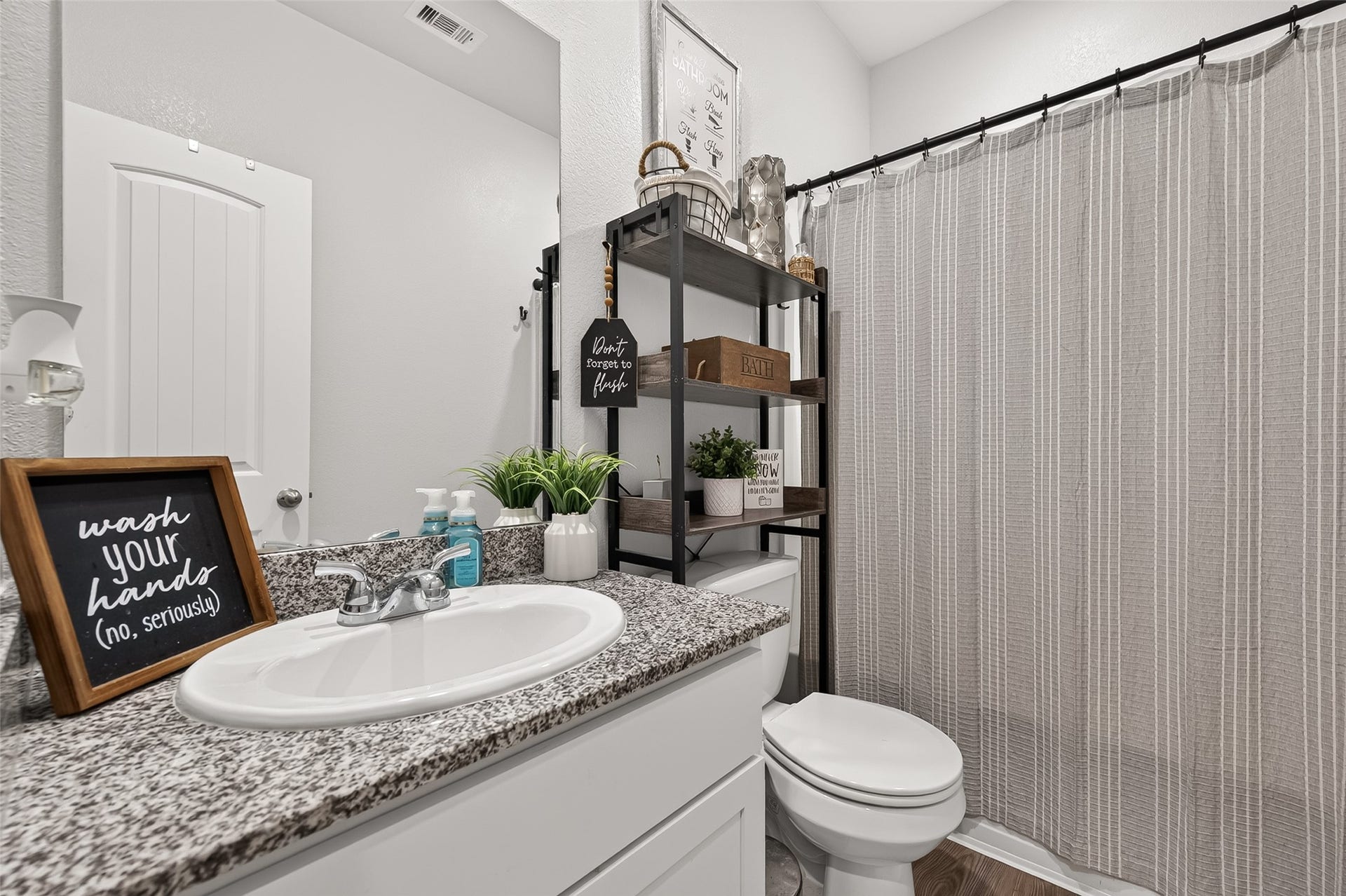 8422 Black Pearl Court, Texas City, TX 77591 Charming bathroom with modern fixtures, featuring a sleek granite countertop, ample shelving for storage, and a stylish shower curtain for a cozy touch.
