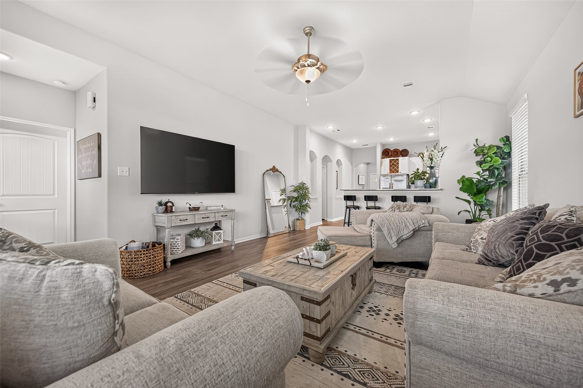 8422 Black Pearl Court, Texas City, TX 77591 Spacious living area with cozy gray sofas and a stylish coffee table, leading to an open kitchen with bar seating. Natural light and elegant decor create a warm, inviting ambiance.