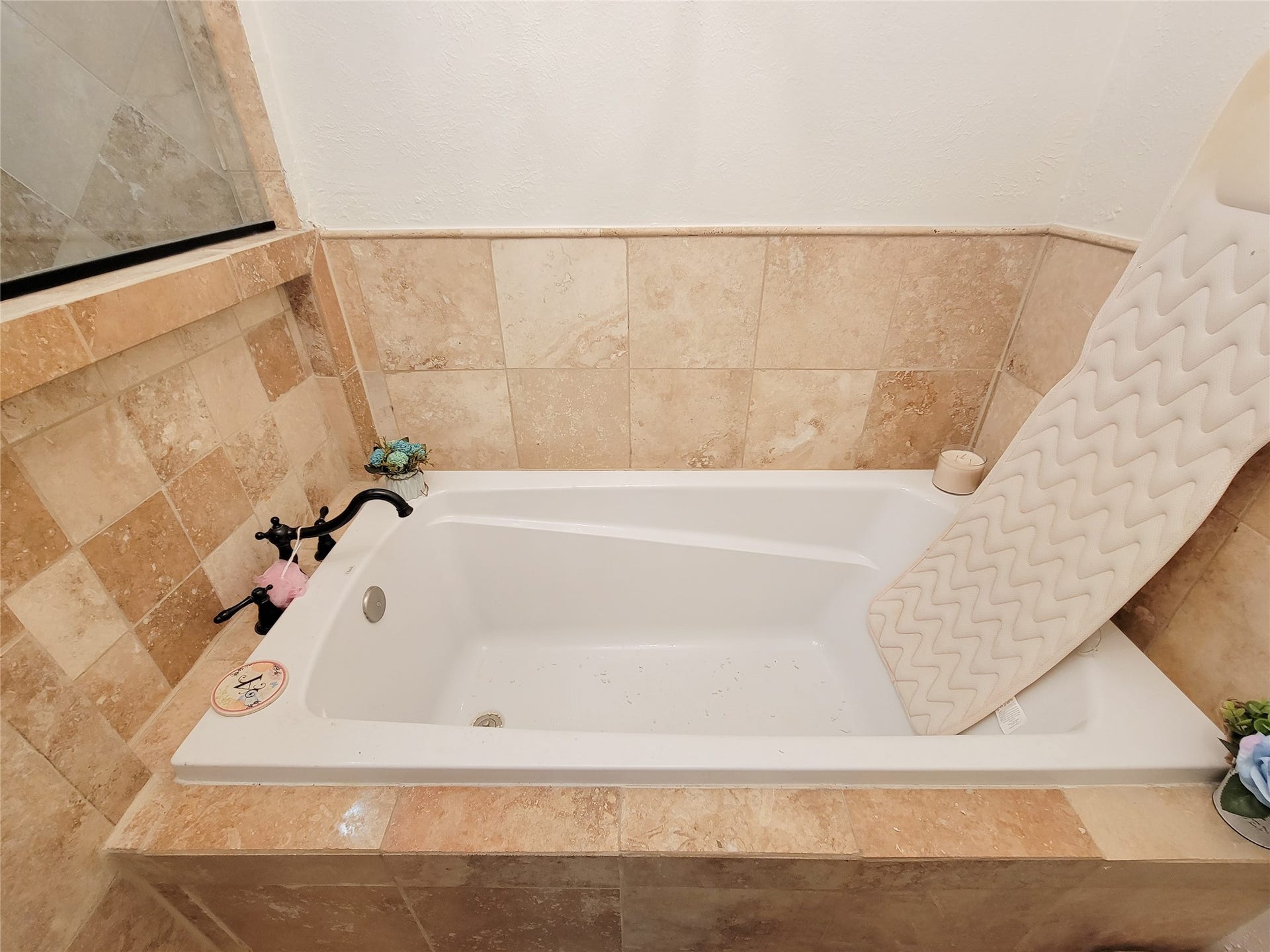 6235 Rolling Water Drive, Houston, TX 77069 This bathroom features a cozy bathtub with beige tile surround, accented with decorative fixtures and a comfortable bath mat.