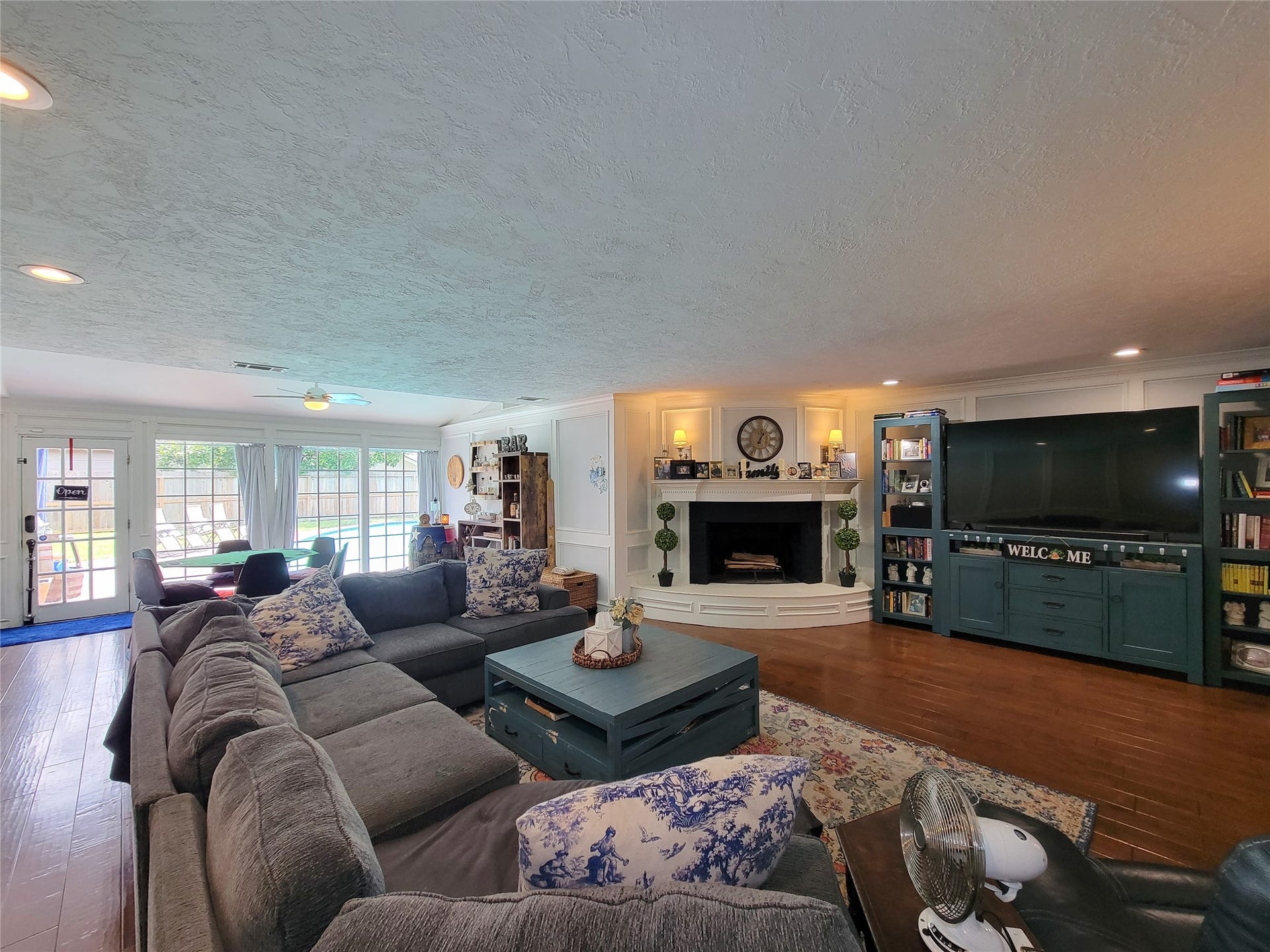 6235 Rolling Water Drive, Houston, TX 77069 This spacious living room features a cozy fireplace, built-in shelving, and a large entertainment area. Ample natural light floods through the glass doors leading to the backyard. The seating area is inviting, making it perfect for family gatherings.