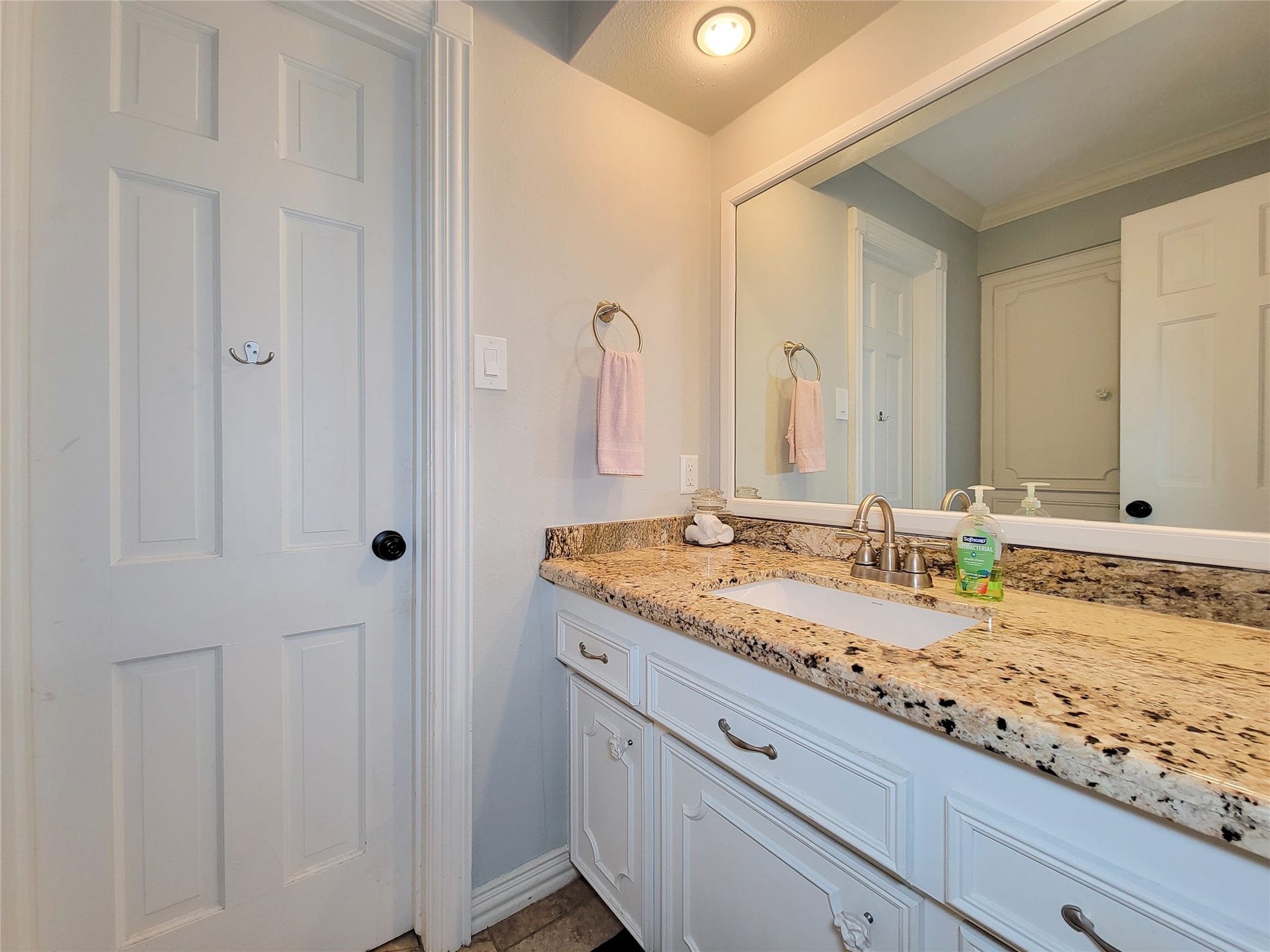 6235 Rolling Water Drive, Houston, TX 77069 This bathroom features a granite countertop with a single sink, white cabinetry, and a large mirror. The neutral tones and simple decor create a clean, inviting atmosphere.