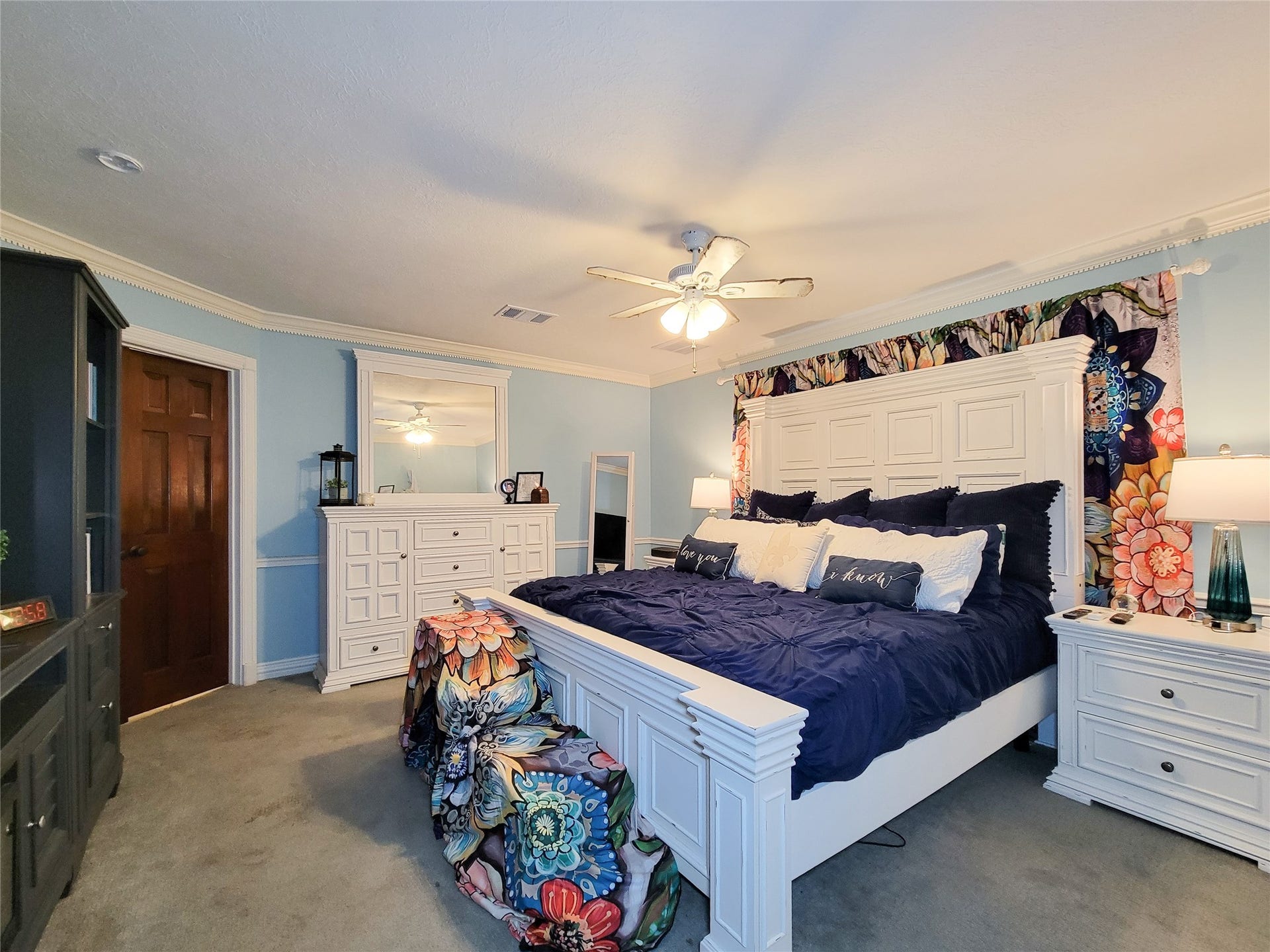 6235 Rolling Water Drive, Houston, TX 77069 This spacious Primary bedroom features a ceiling fan, soft lighting, and colorful floral accents, creating a cozy and inviting atmosphere.