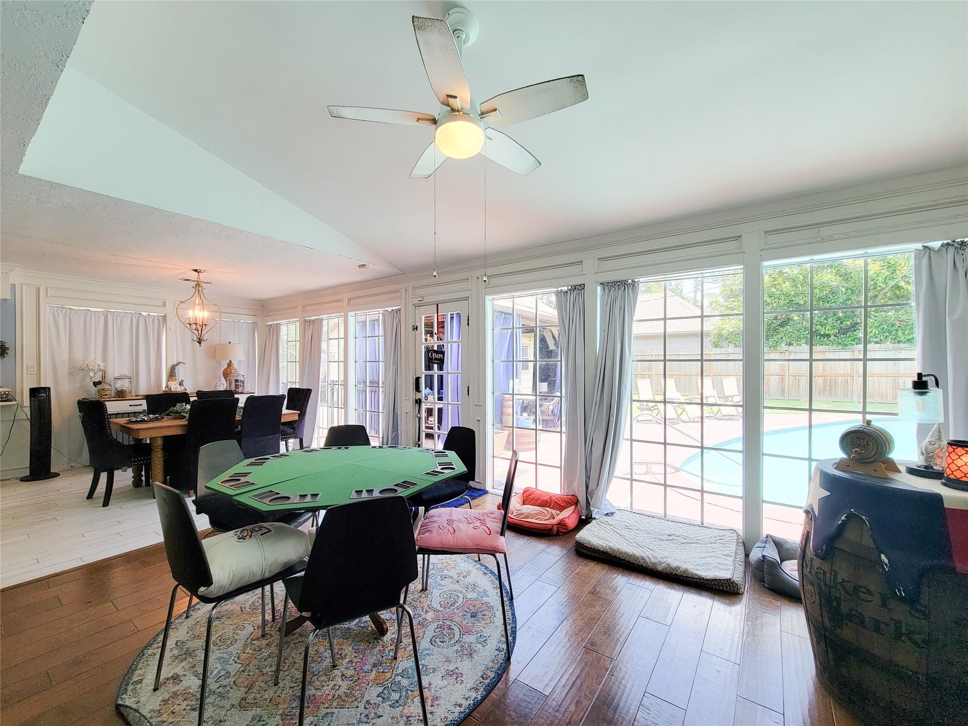 6235 Rolling Water Drive, Houston, TX 77069 This inviting room features a spacious open layout with large windows overlooking a backyard pool. It includes a dining area with elegant lighting and a cozy seating space, ideal for entertaining and relaxation.