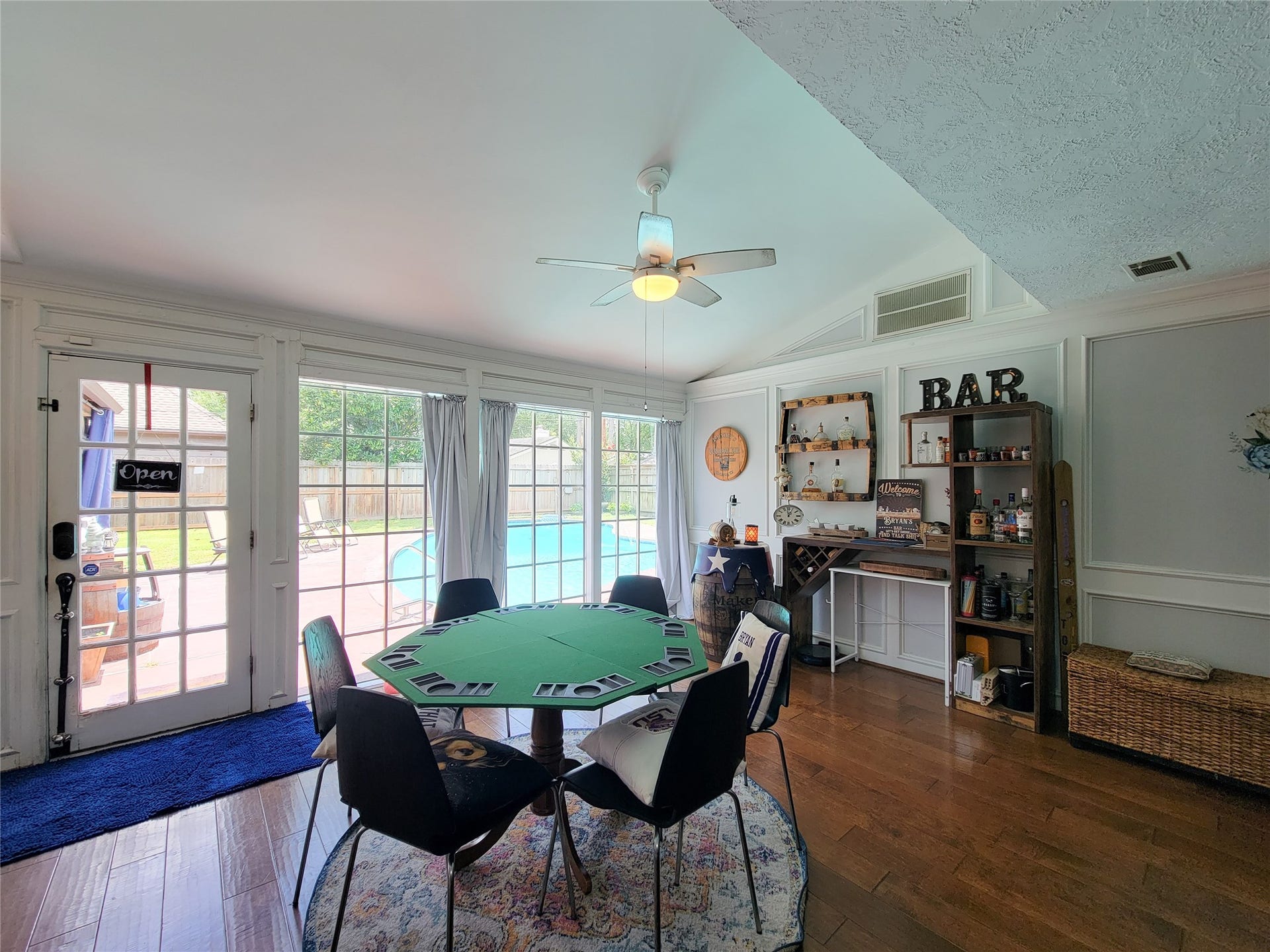 6235 Rolling Water Drive, Houston, TX 77069 This room features a cozy entertainment area with wooden flooring and a built-in bar. Large windows and French doors offer abundant natural light and a view of the pool, creating a perfect space for gatherings and relaxation.