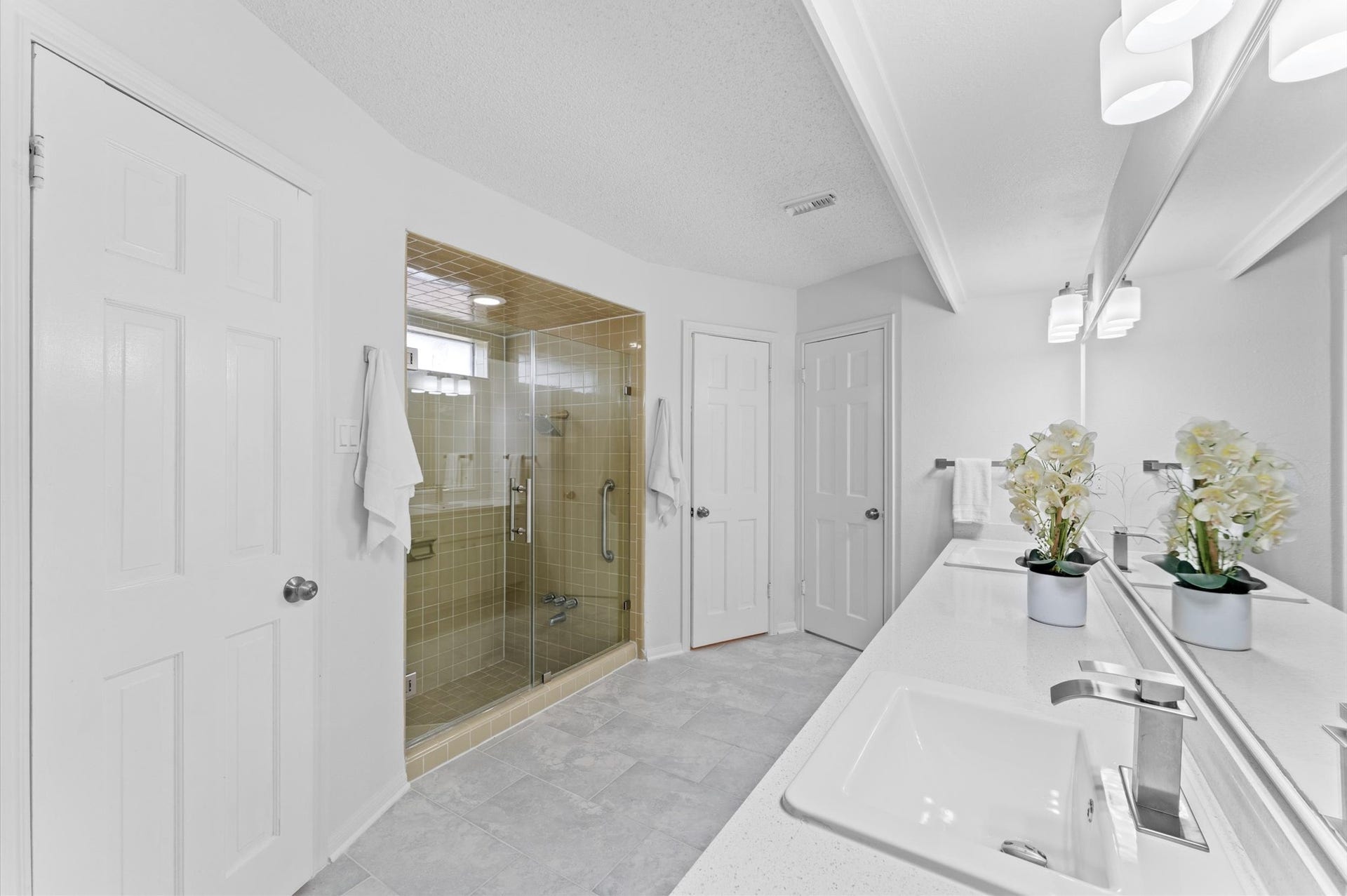 A large frameless shower is equipped with a convenient safety bar.