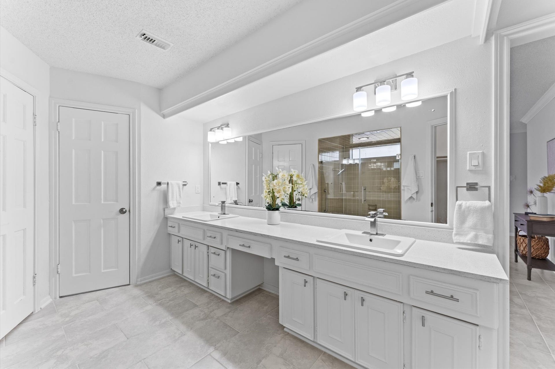 The primary bath features a dual sink vanity, a large framed mirror, and intricate lighting.