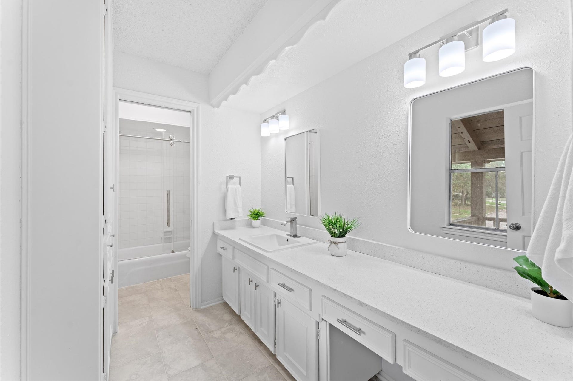 A roomy second bath includes a linen closet, a spacious counter with two mirrors, one that rests over a built-in vanity.