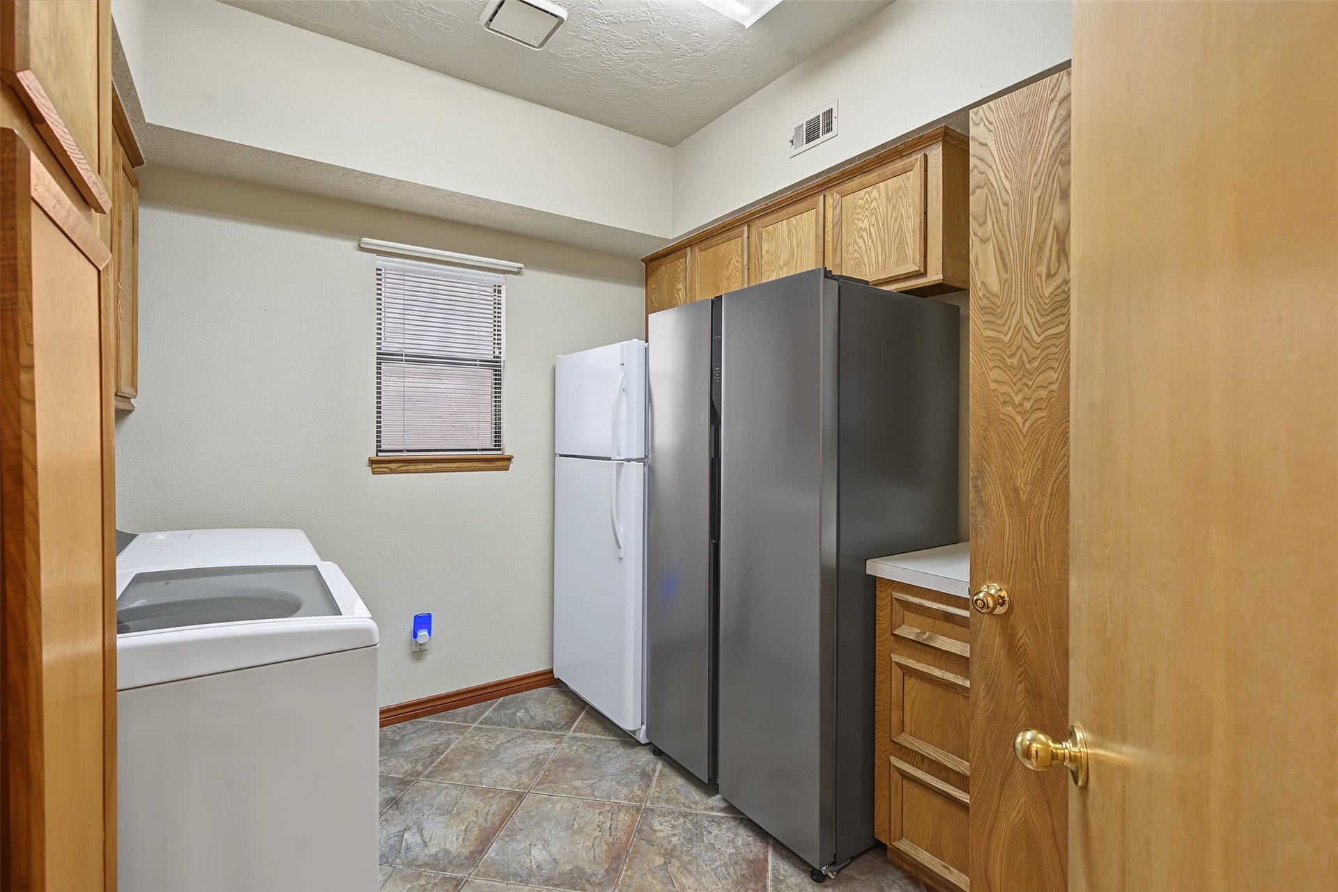 Oversized laundry room with plenty of storage, a sink and half bathroom.