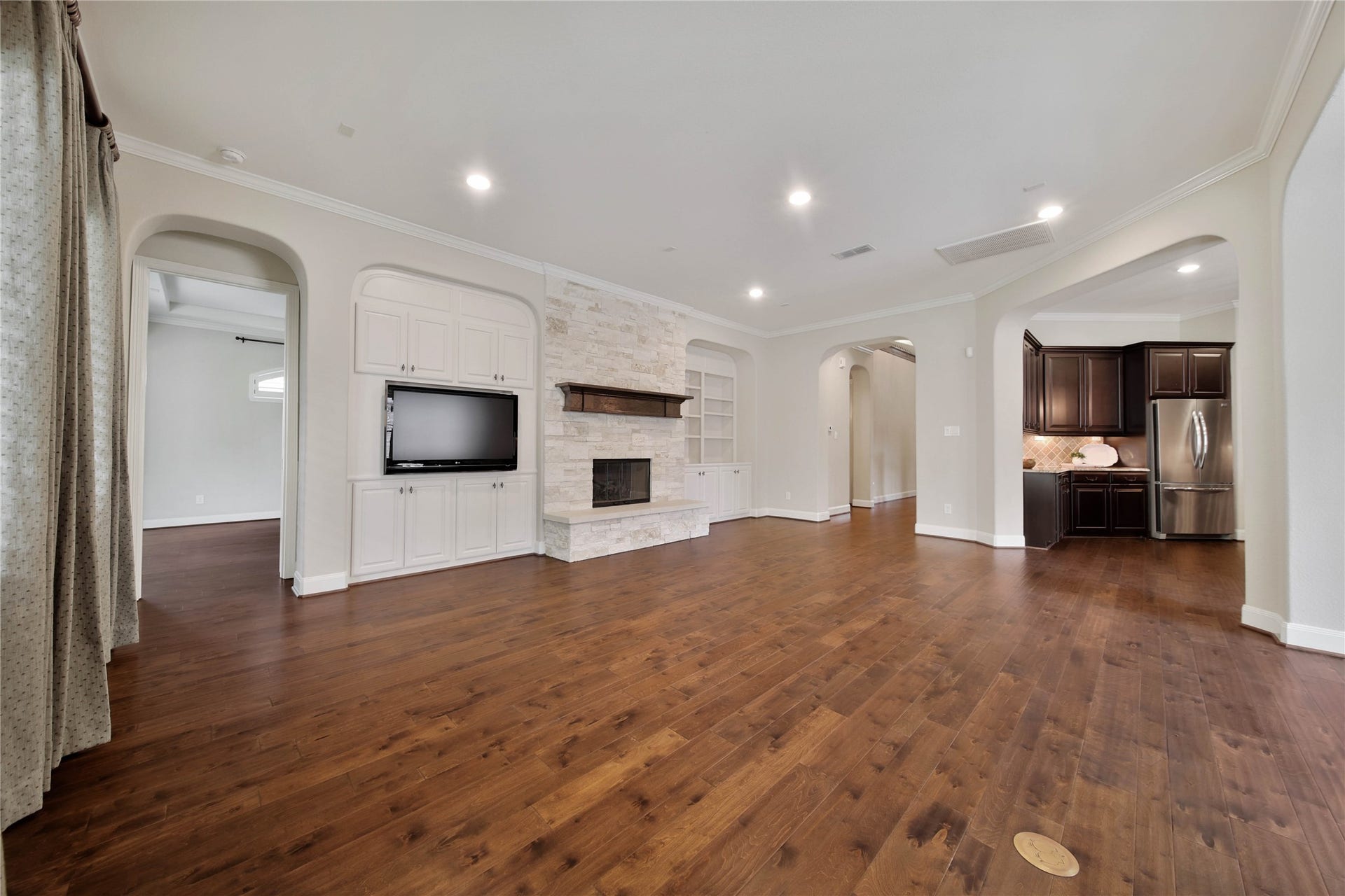 The spacious living area is designed for comfort and style, featuring a built-in entertainment center and a beautiful floor-to-ceiling stone gas log fireplace that anchors the room.