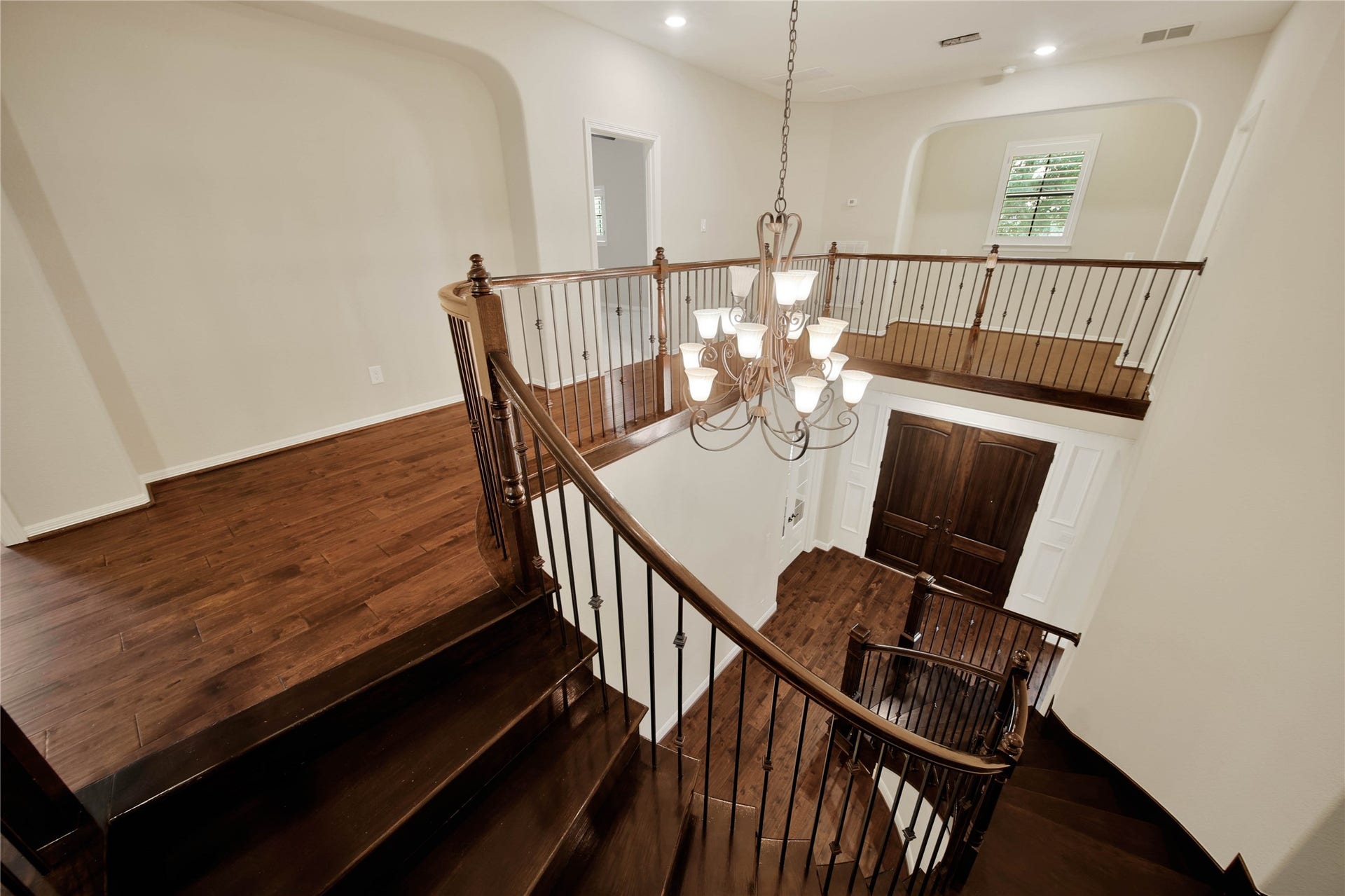 The elegant sweeping wood staircase creates a striking architectural feature, leading to the second floor while a sizable closet beneath provides a clever and practical storage solution.