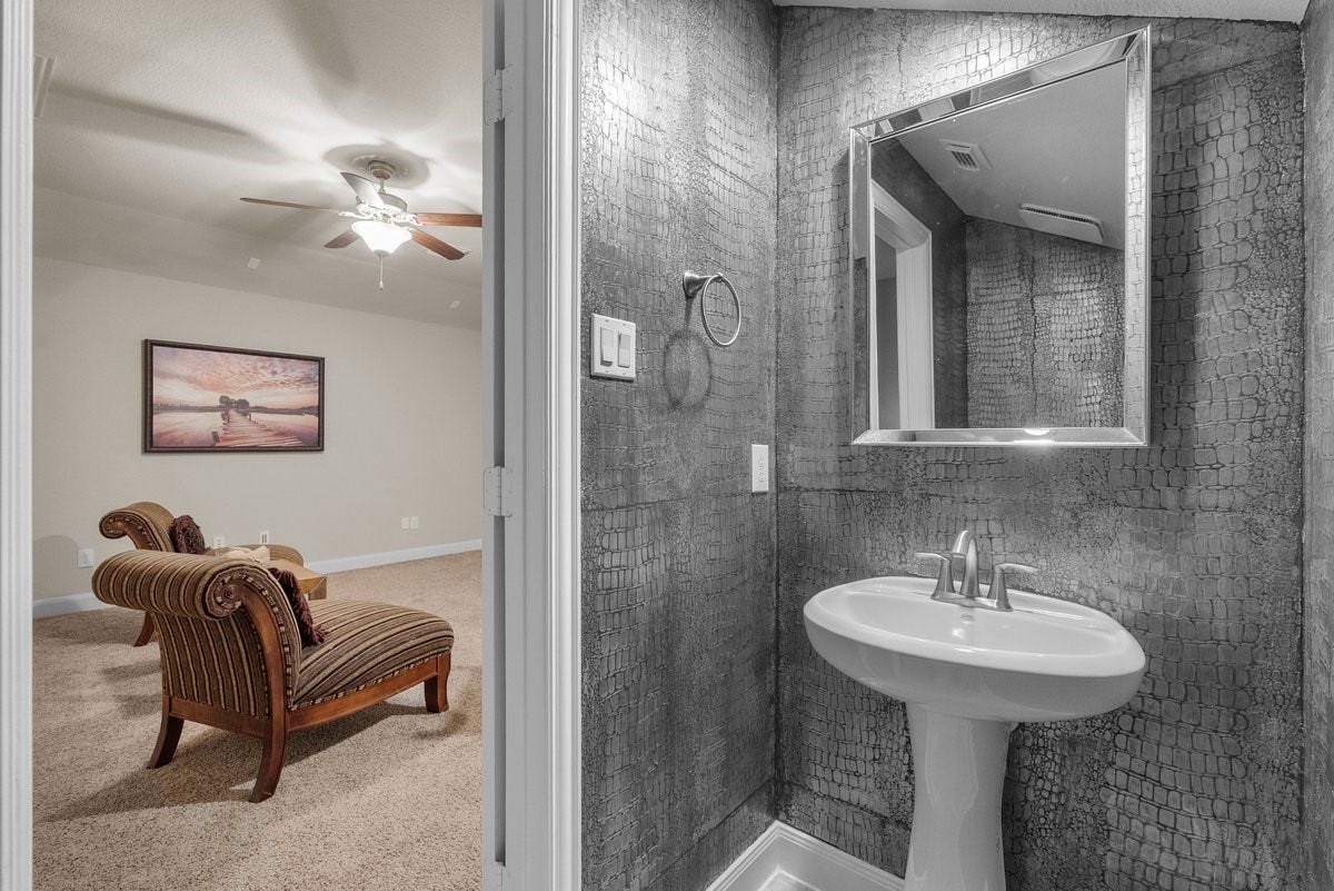 416 Via Regatta Drive, Webster, TX 77598 Bespoke artisan style! The half bath off the game room showcases an incredible, professionally hand-painted faux-croc texture with a rich metallic finish. This stunning space blends creative design with modern functionality, featuring elegant tile floors and high-end fixtures.