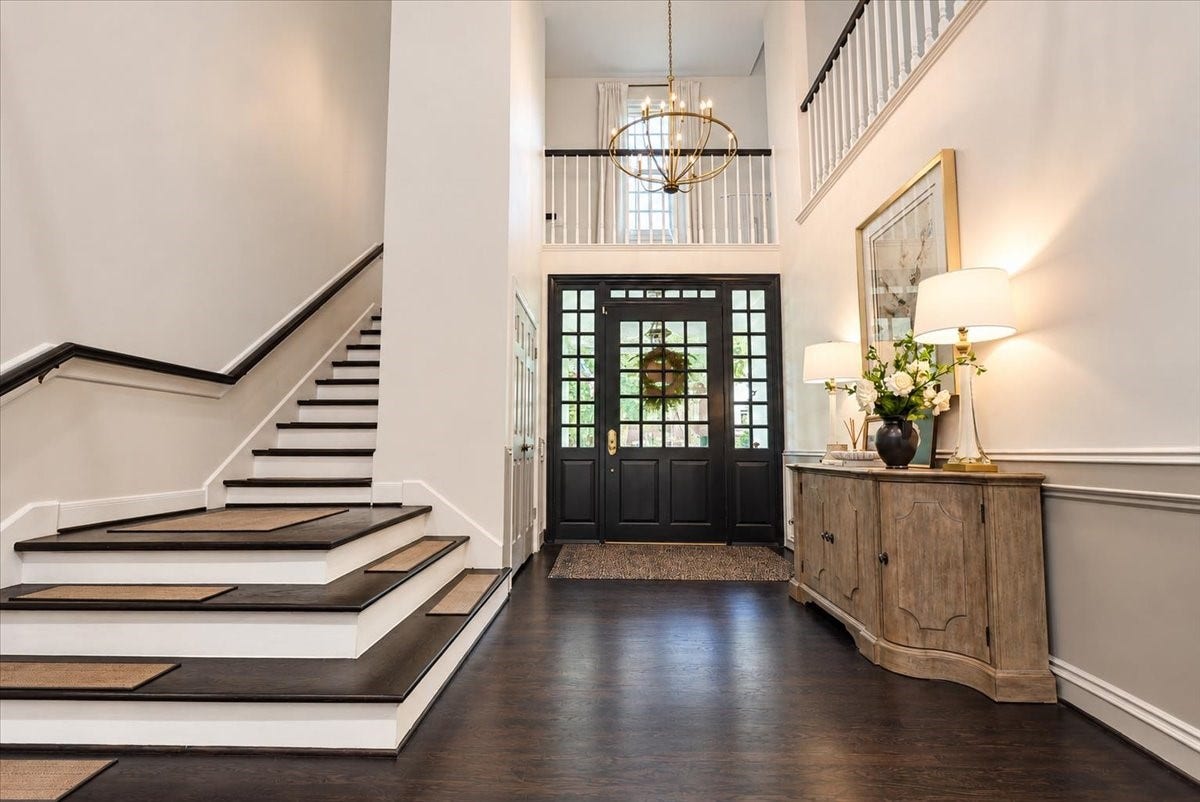14026 Champions Hamlet Court, Houston, TX 77069 Step into a grand first impression in this dramatic two-story foyer, where a sweeping staircase with dark treads and crisp white risers, classic wainscoting, and a gleaming chandelier create an inviting arrival.