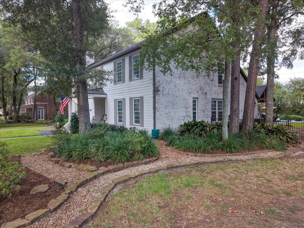 14026 Champions Hamlet Court, Houston, TX 77069 German schmear applied across the brick in 2022 gives the home a soft, refined finish, framed by gray shutters, mature trees, and stone-edged landscape beds.