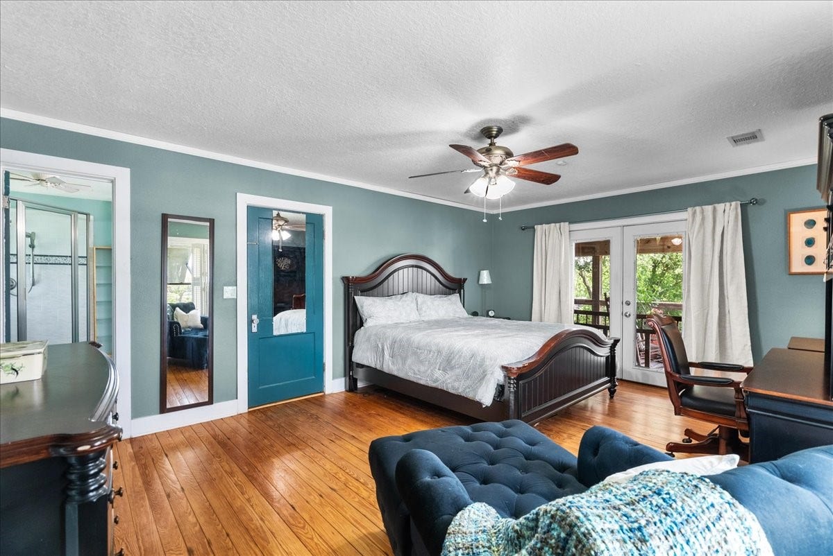 939 17th Street, Dickinson, TX 77539 Spacious primary bedroom with hardwood flooring, multiple windows, French doors to the outdoor space and room for an additional sitting or workspace area