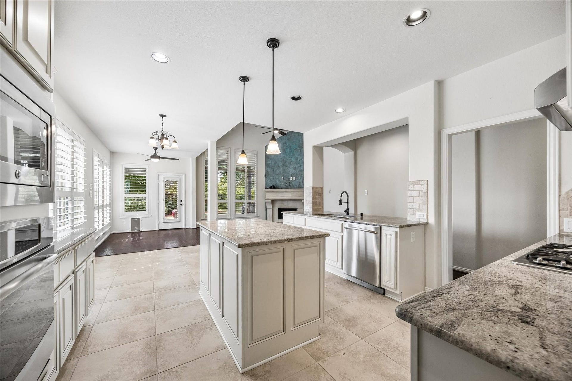A wide opening above the sink connects the kitchen to the family room, keeping the handsome fireplace in view.