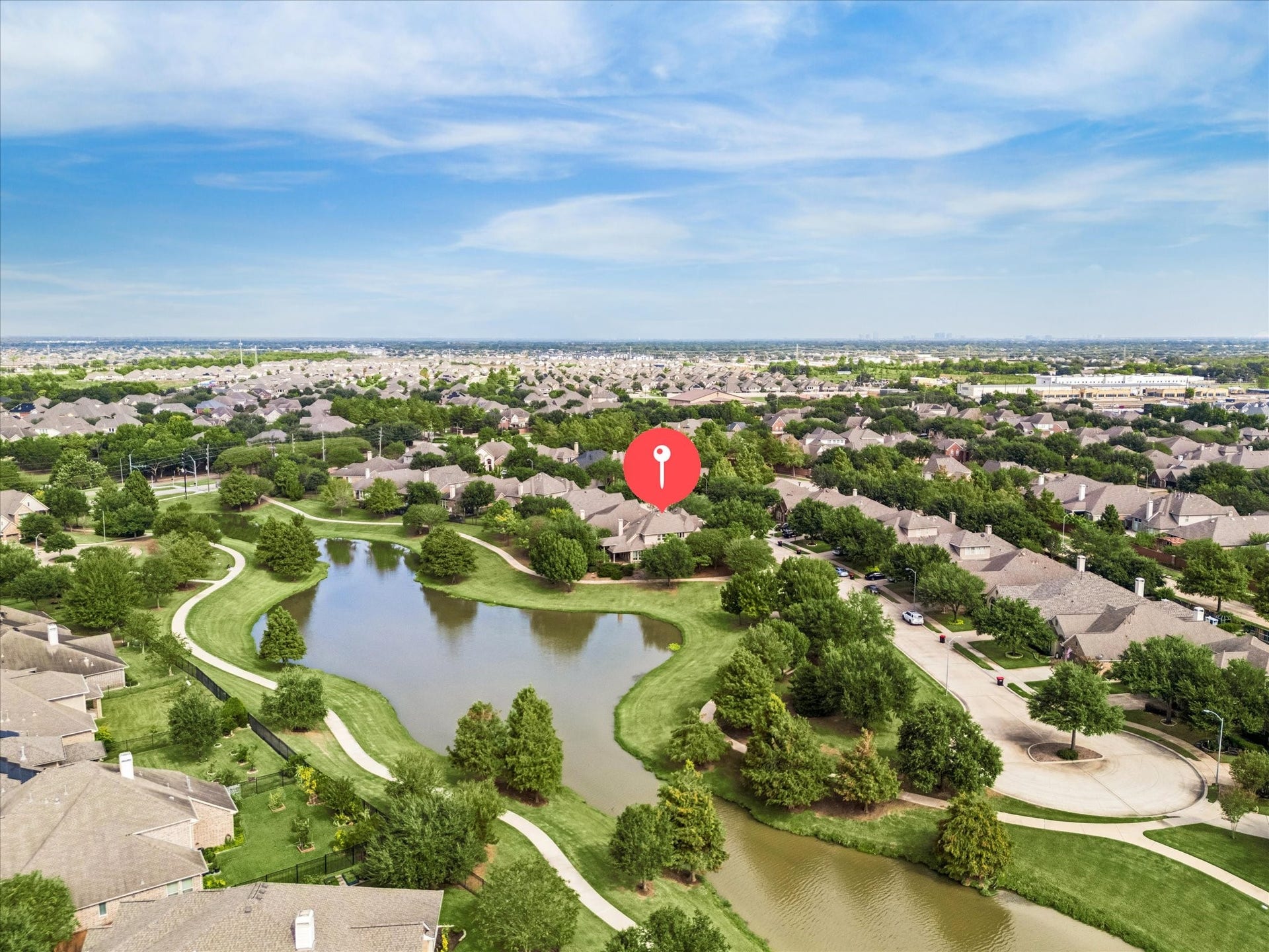 Aerial view highlights the home's scenic lakeside setting, with winding walking trails and green space extending behind and alongside the property.