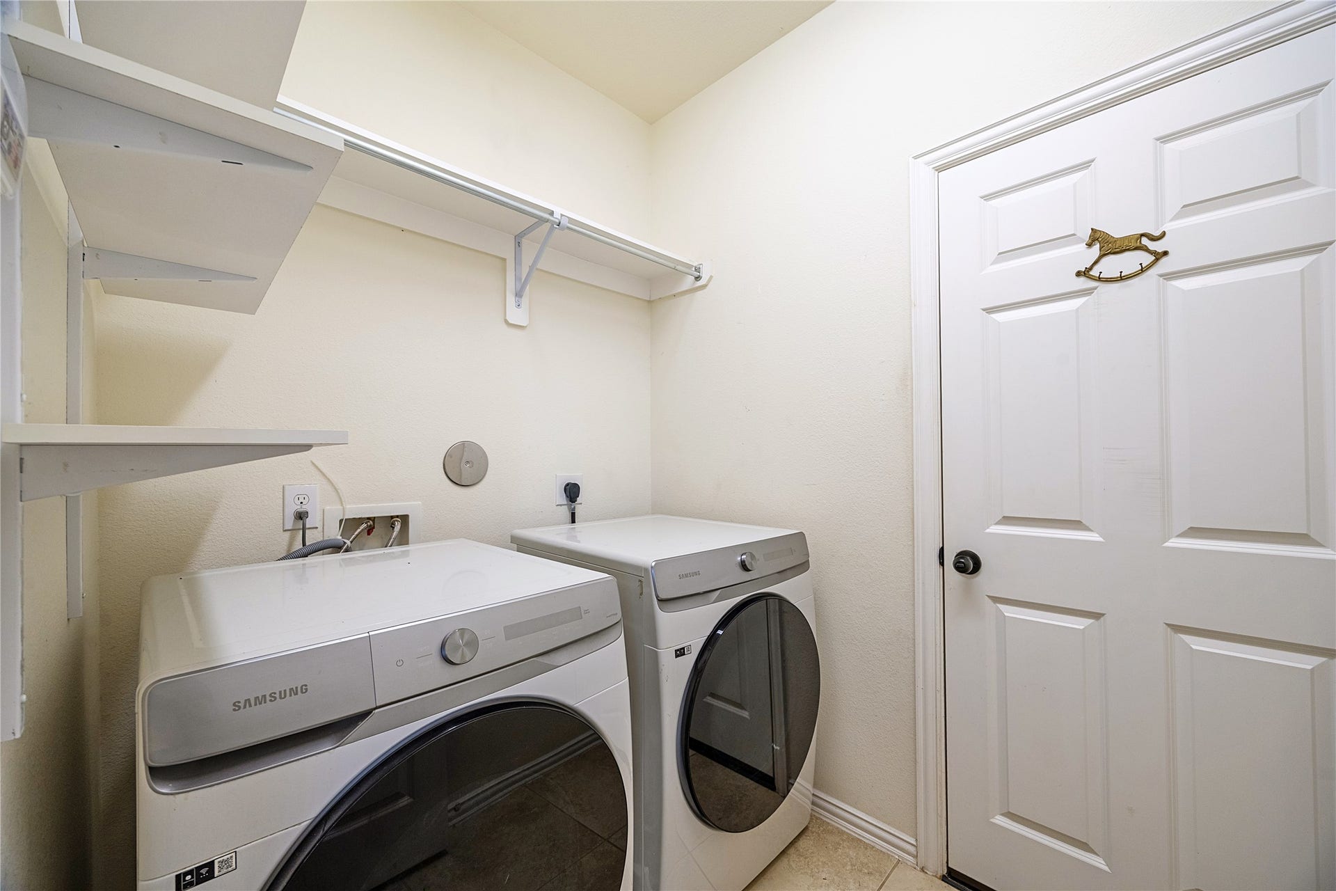 Laundry room with open shelving, a hanging rod, and space for a side-by-side washer and dryer. Direct access to the attached garage.