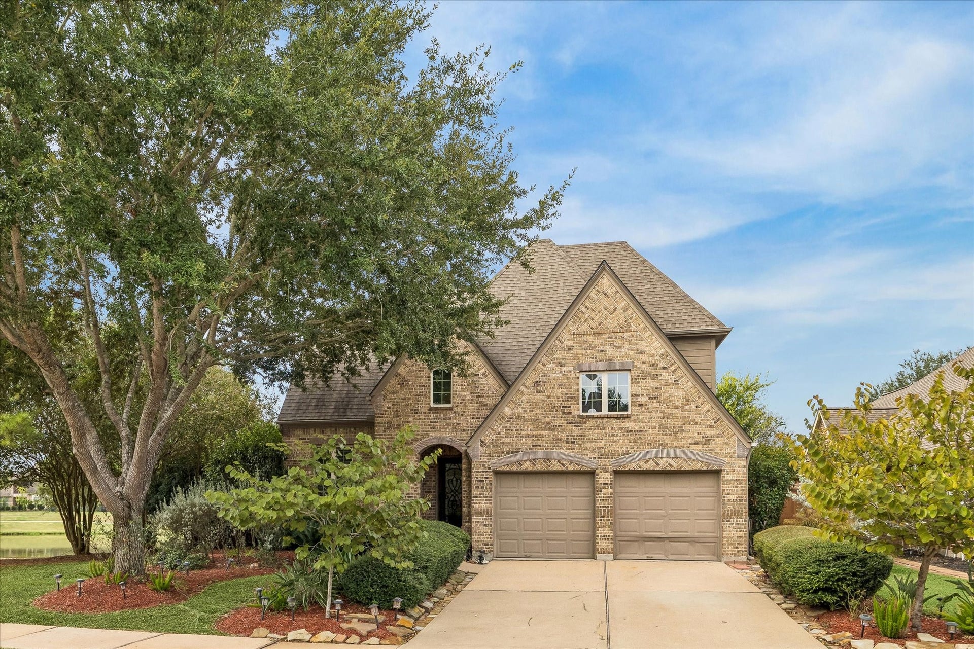 Beautifully framed by mature trees and manicured landscaping, this inviting home pairs classic brick and stone architecture with peaceful water views