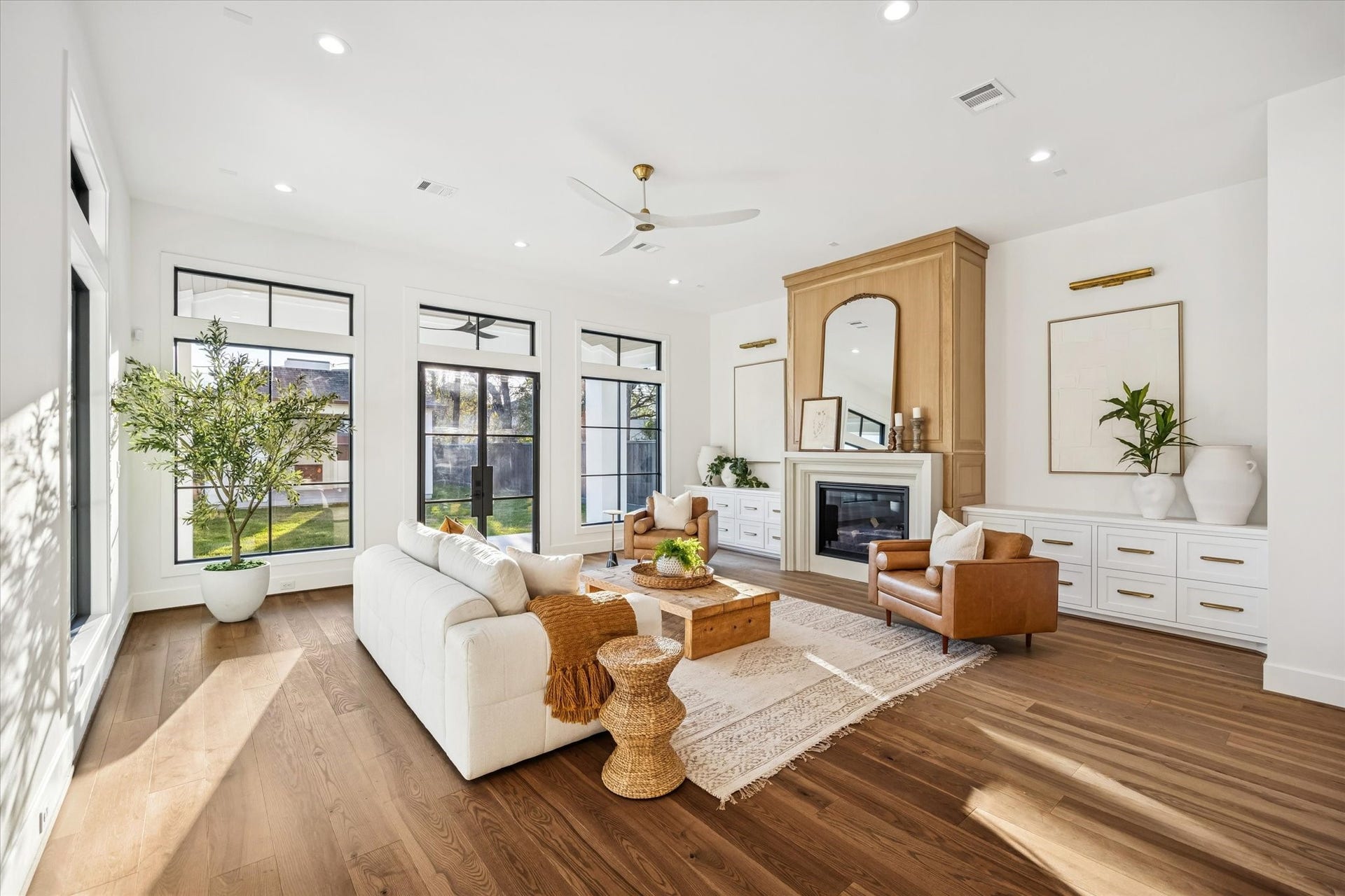 Main living room is framed by tall windows and glass doors that draw in natural light and connect directly to the backyard. The generous footprint and centered fireplace create a comfortable gathering space designed for both daily living and entertaining. **Previous build by Arch Angelo**