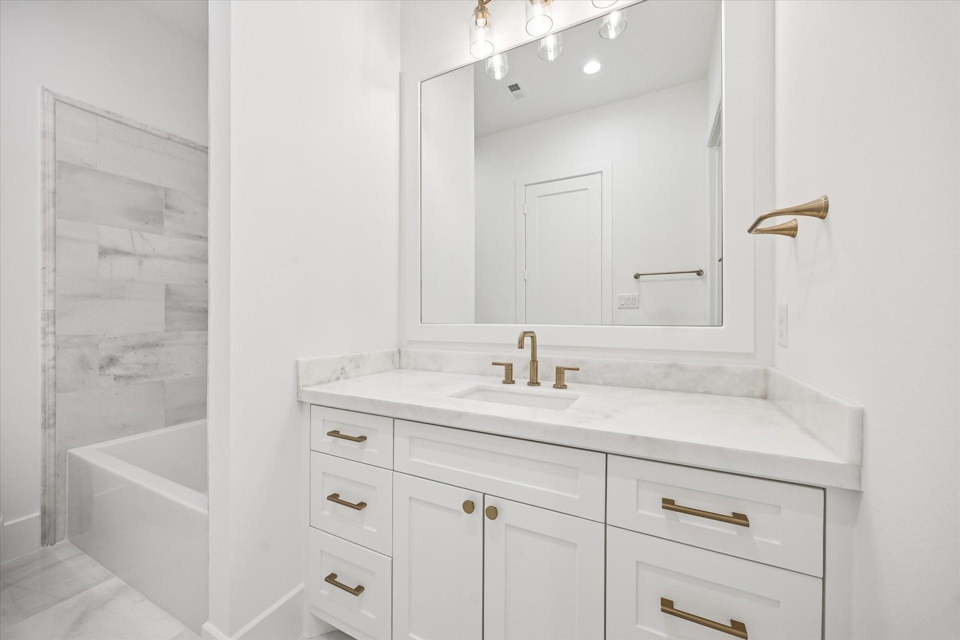 Clean, spa inspired finishes pair with a tub and shower combination designed for everyday ease. Stone countertops, generous vanity storage, and modern fixtures create a polished space that feels both timeless and practical.**Previous build by Arch Angelo**
